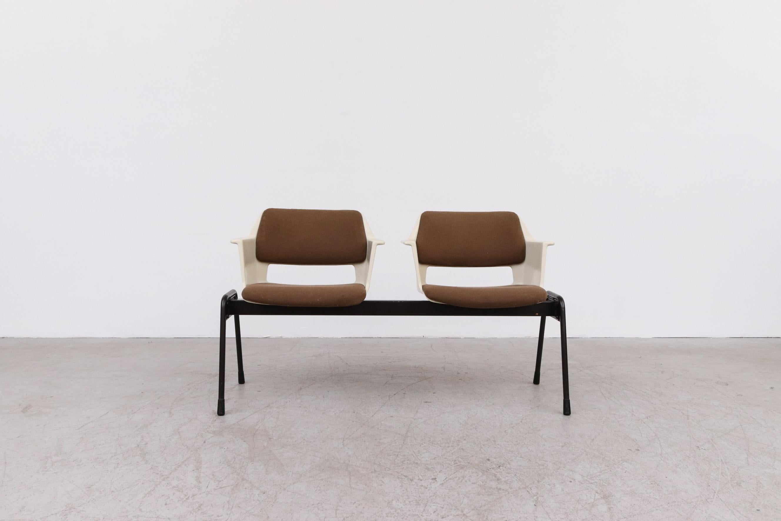 Double bucket seated bench by A.R. Cordemeyer for Gispen. Acrylic cast bucket shell seats with original brown upholstered seating on a black enameled tubular metal frame. In original condition with visible patina. Wear consistent with its age and