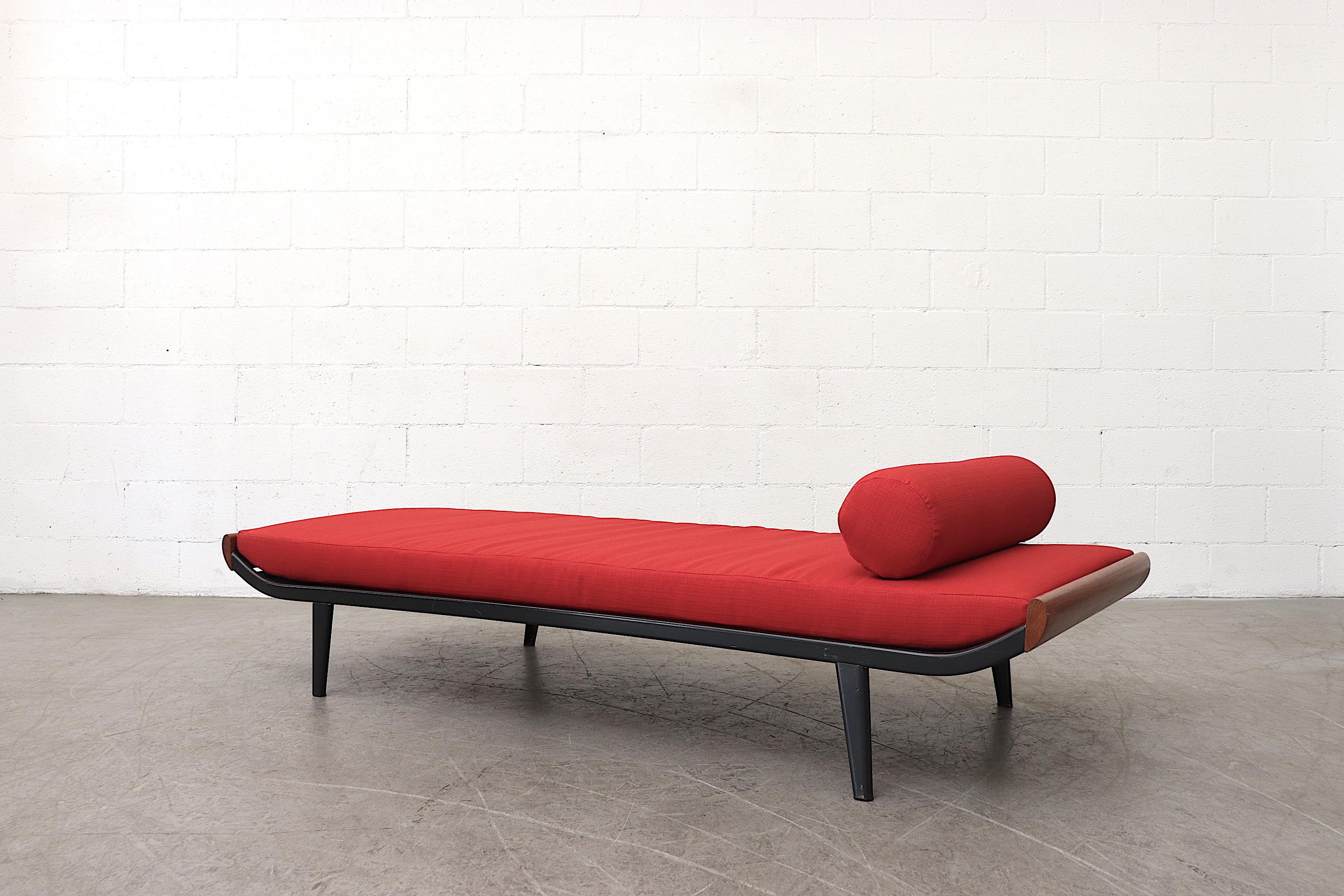 1960s Cleopatra daybed by A.R. Cordemeyer. Teak ends with dark enameled metal frame and new red upholstered mattress with matching bolster. Frame in original condition with expected wear. Frames may vary from the one pictured. Other sizes and color