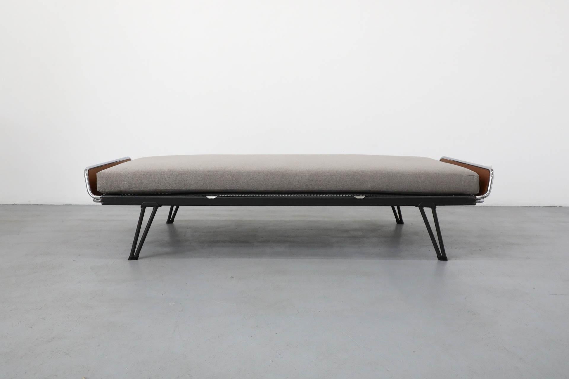 Newly upholstered light grey mattress on a dark grey enameled metal frame with chrome and teak ends, and signature 