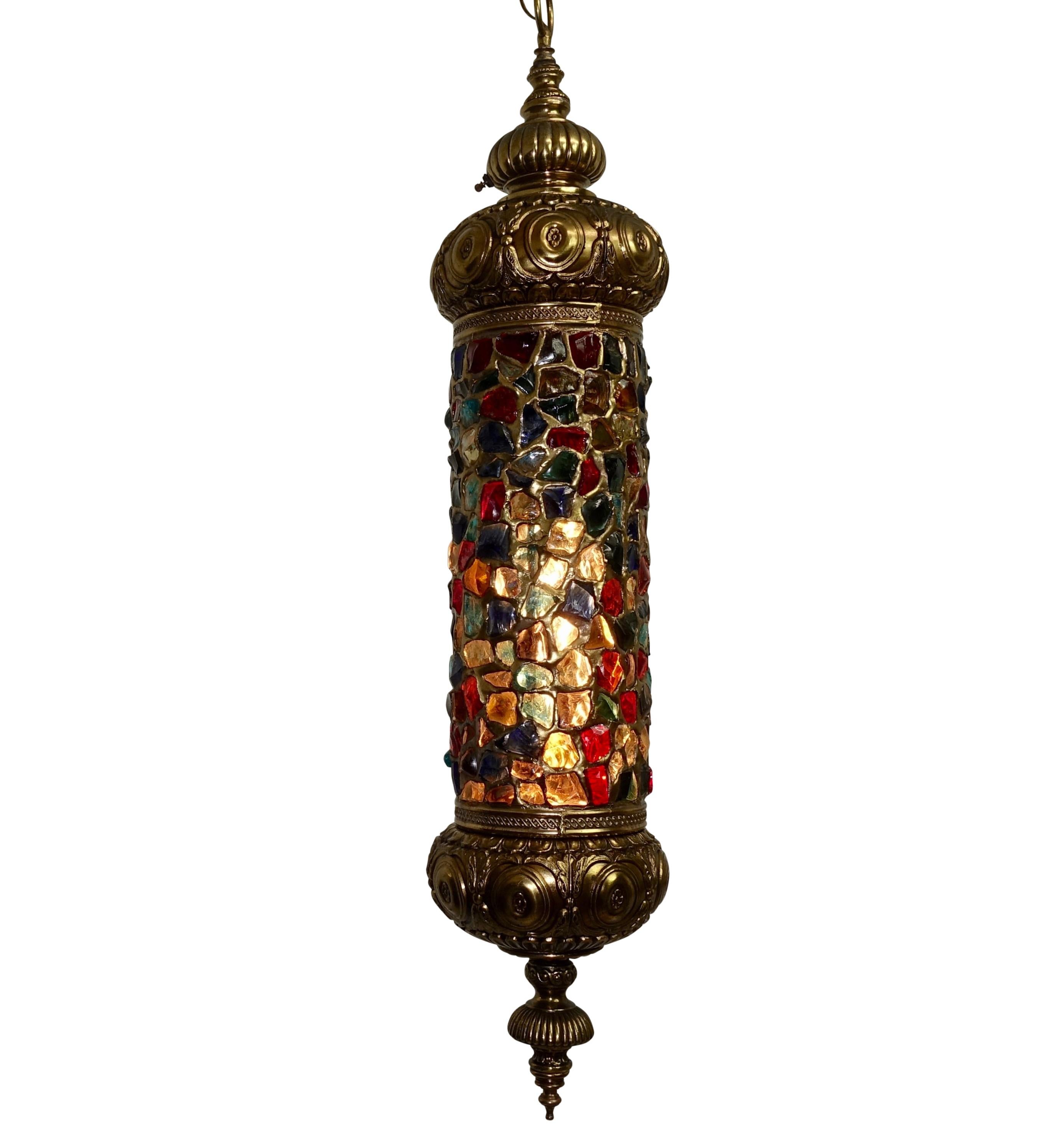 Wonderfully colorful Arabesque style brass and multi colored jewel glass hanging light with pressed design in the brass top and bottom. Reds, blues, clear, greens, yellows, throughout. American, circa 1940.
Measurements below include canopy and