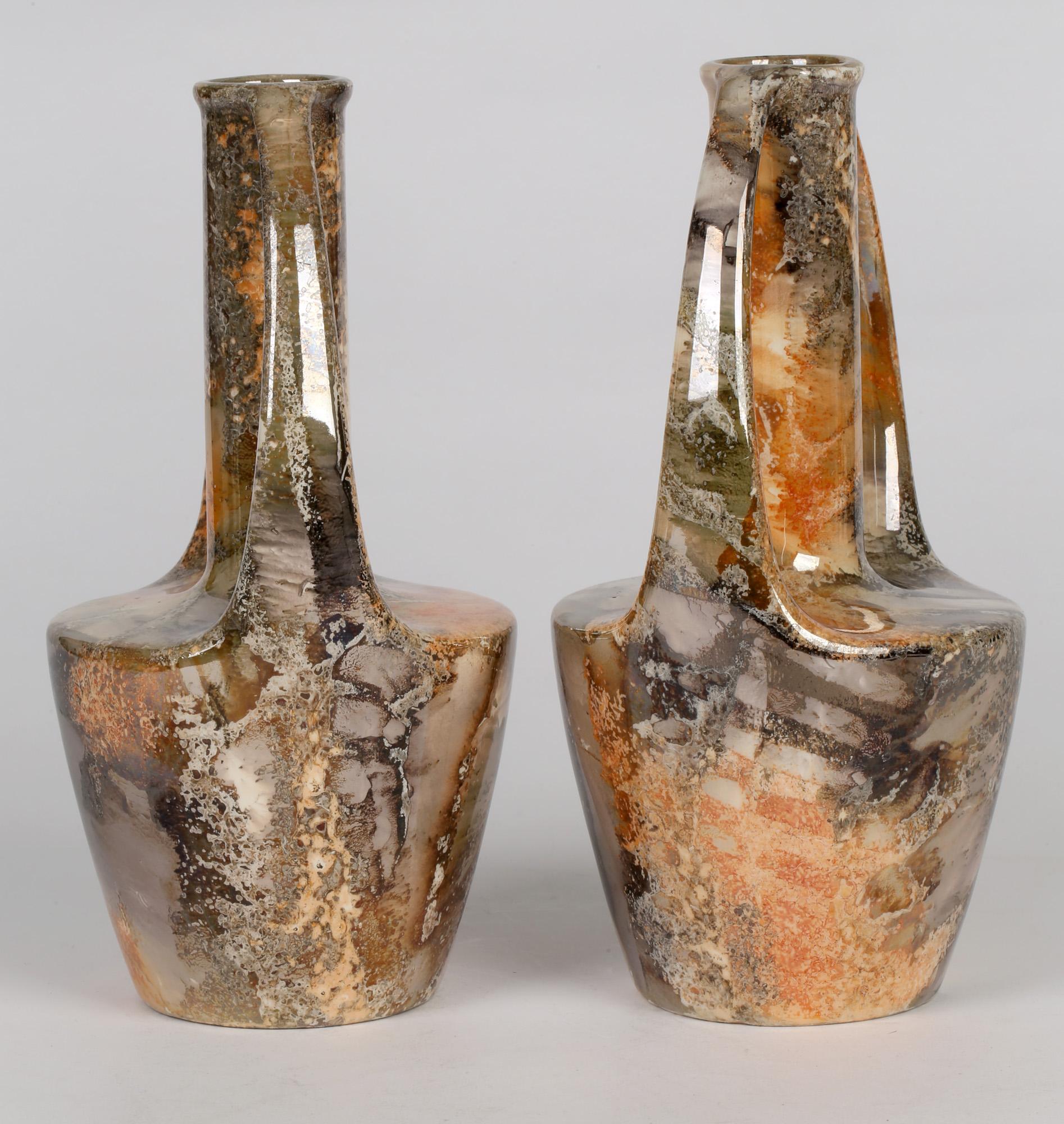 A stunning and scarce pair Finnish Art Deco twin handled art pottery vases decorated in lustre glazes by Arabia and made between 1917 and 1927. The earthenware vases have a rounded flat topped lower body with a central funnel shaped tall neck and