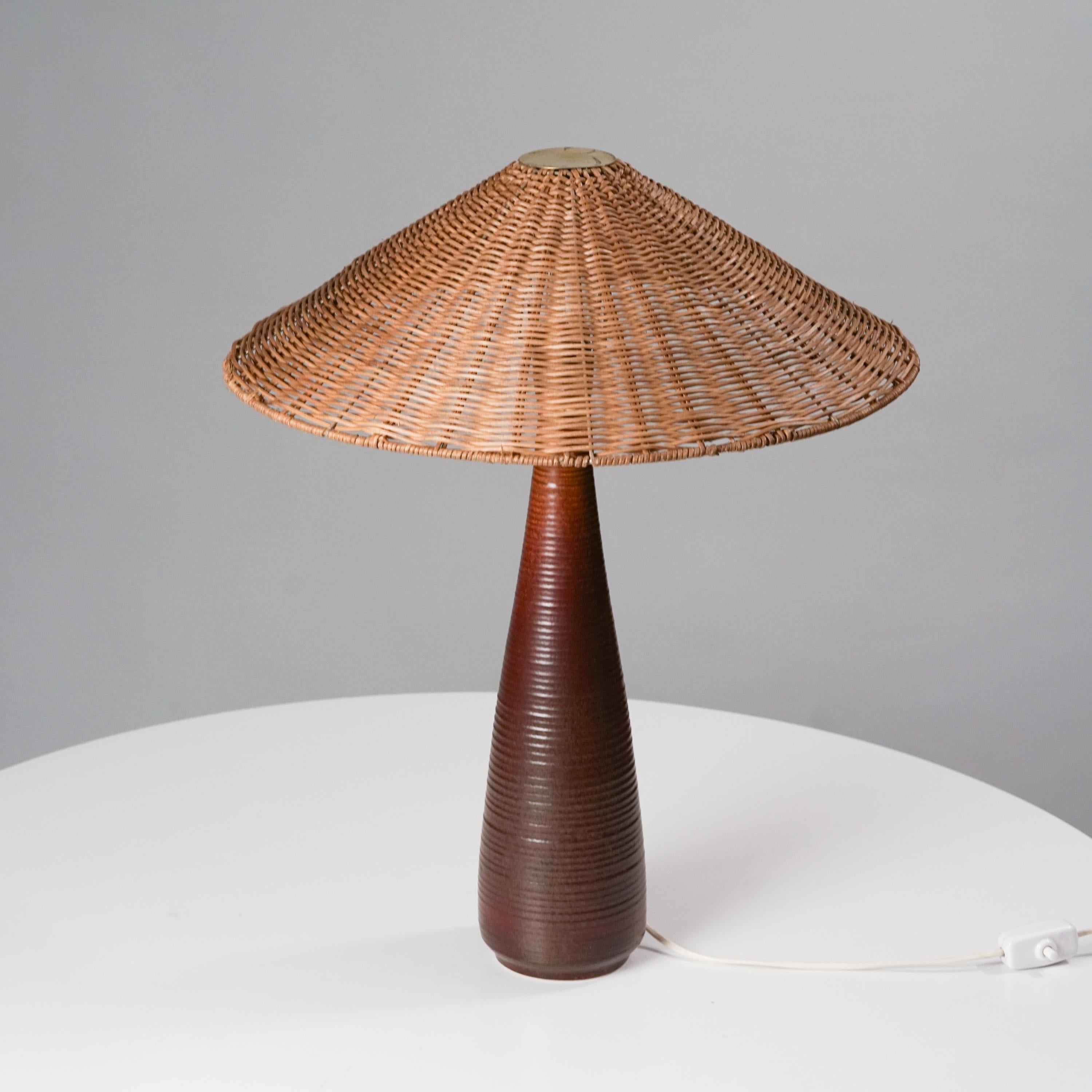 Lampe de table Arabia modèle 9-55 des années 1950. Cadre en céramique émaillée avec abat-jour en osier. Détails du laiton. Bon état vintage, patine mineure correspondant à l'âge et à l'utilisation. 

