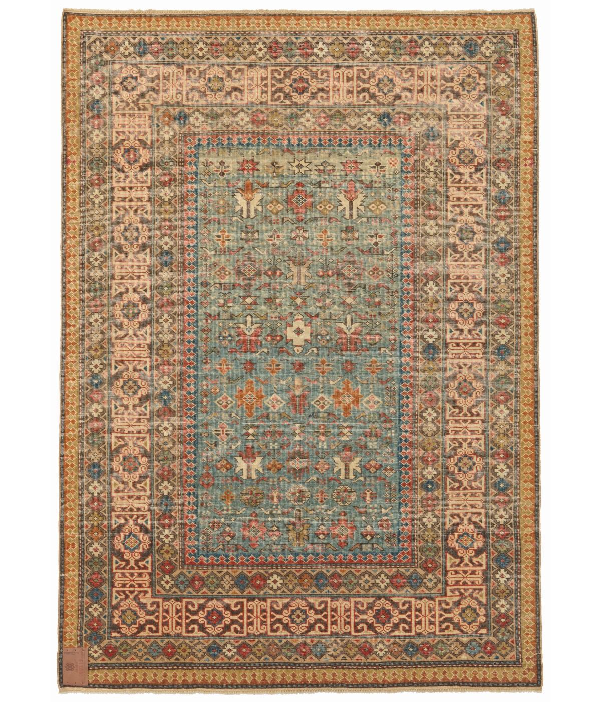La fuente del diseño de la alfombra procede del libro Oriental Rugs Volume 1 Caucasian, Ian Bennett, Oriental Textile Press, Aberdeen 1993, nº 360. La hilera alternada de octógonos y flores puntiagudas estilizadas es típica de un grupo llamado