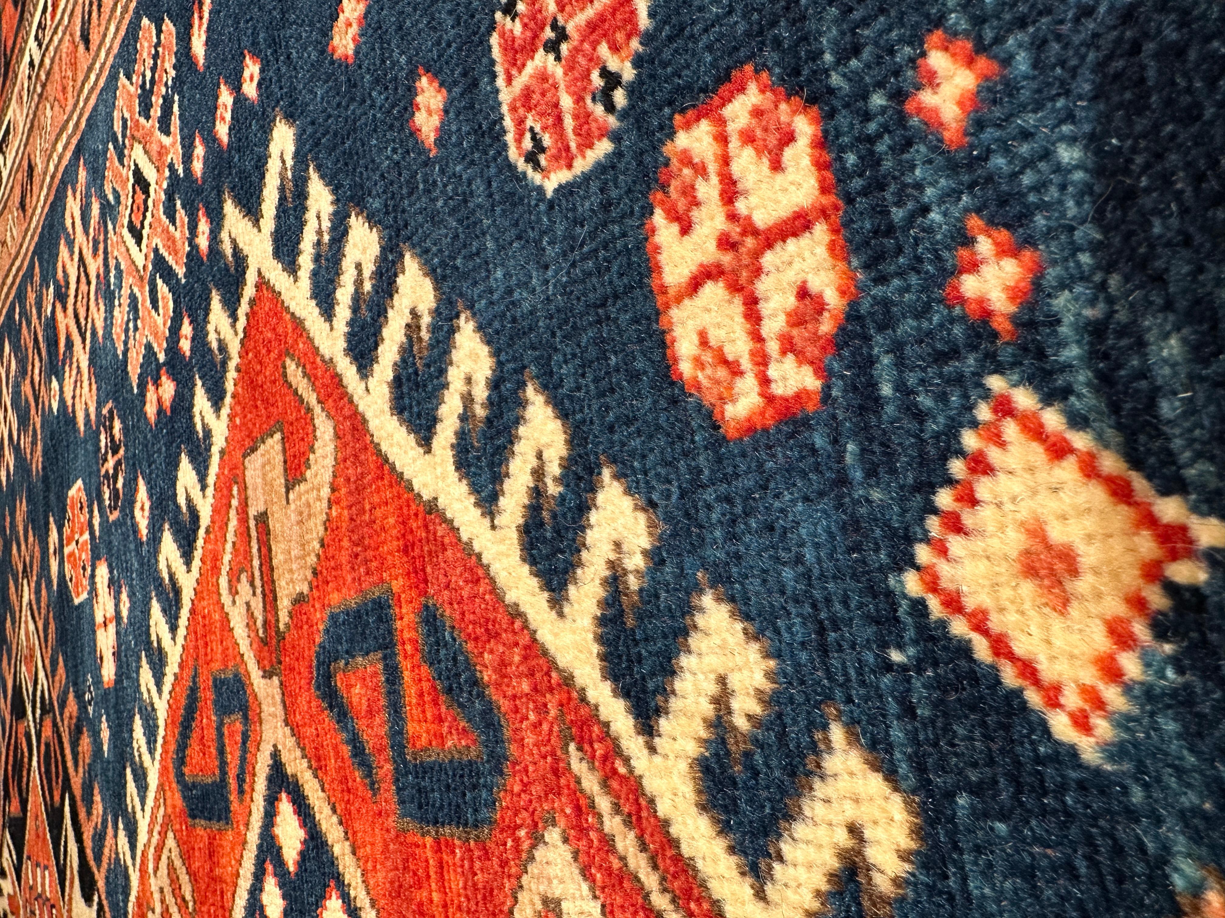This is a complete hooked field with double medallions rug from the late 19th century, Kazak region, Caucasus area. A striking field design features three medallions each with concentric hook motifs, with S patterns in the center of the medallions.