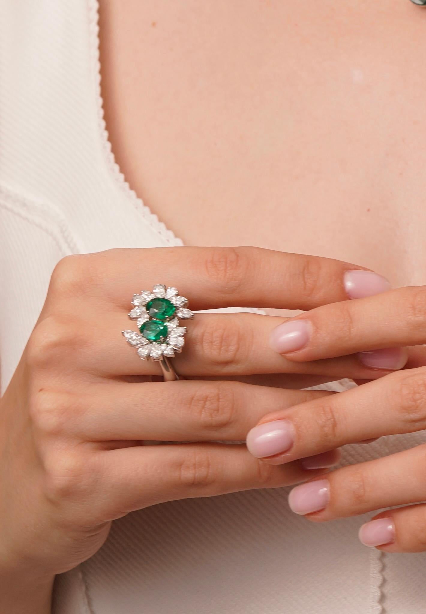 Une élégante bague Toi et Moi mettant en valeur deux émeraudes de Zambie totalisant 2,36 carats, magnifiquement complétées par une grappe de diamants taillés en poire et en marquise pesant au total 2,98 carats. Fabriqué en or 18k avec un poids de