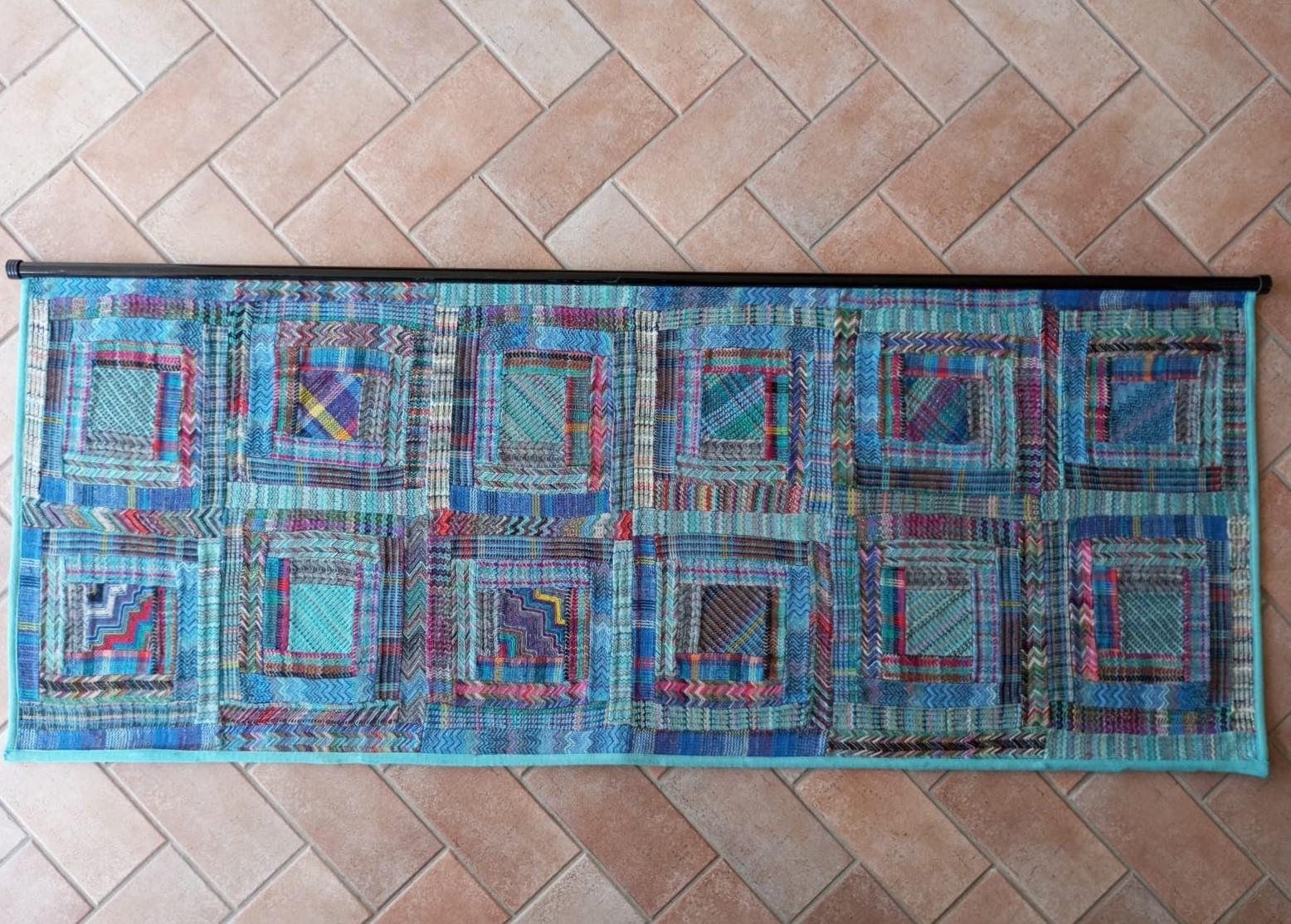 
Tapisserie d'Ottavio Missoni au design typique de son style. Caractérisé par des carrés répétés dans des tons de bleu. Les textures et les couleurs alternent, créant une profondeur et un dynamisme visuel. Le bord extérieur est fini dans un ton noir