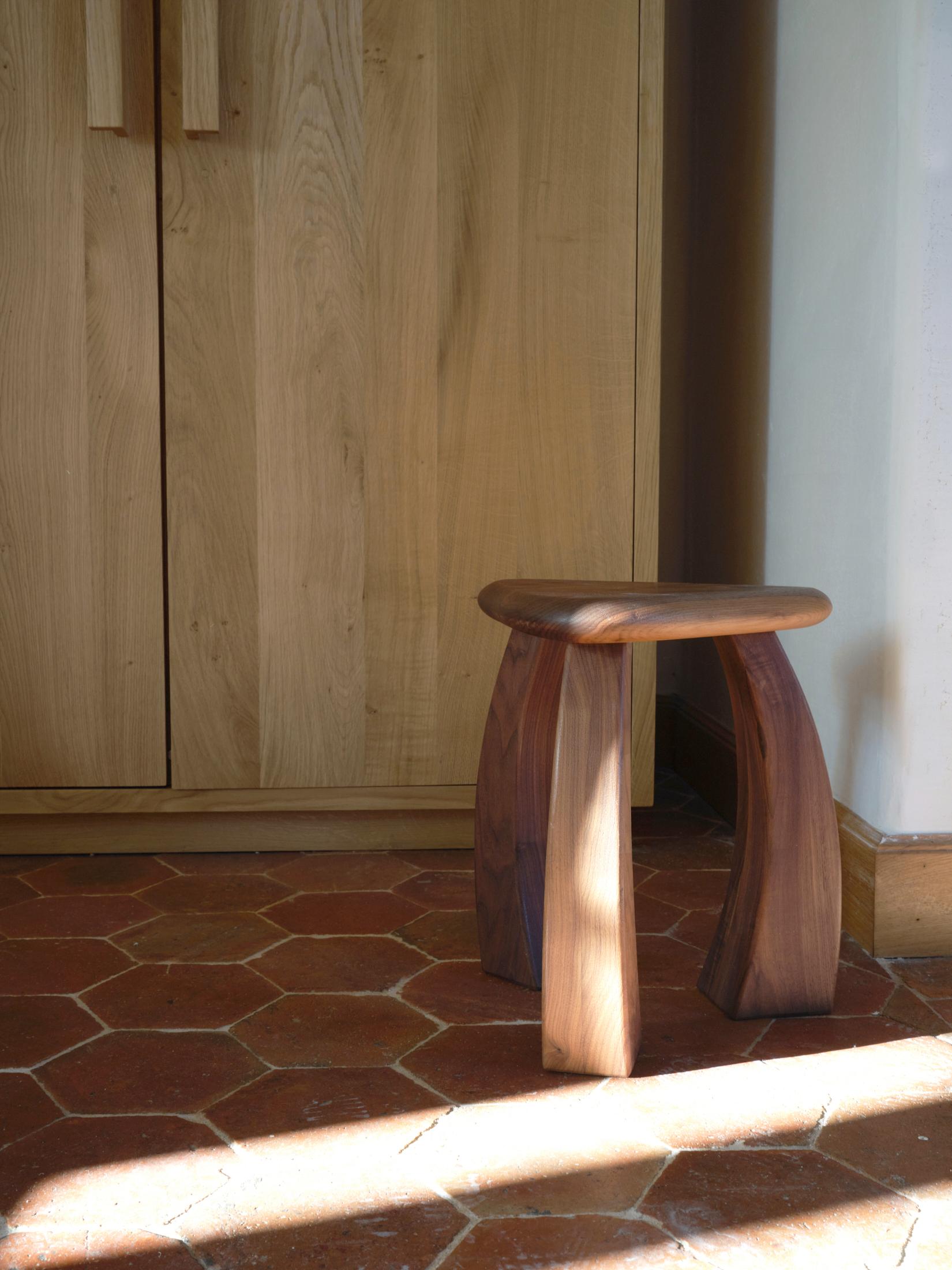 Taburete Arc de 37 en nogal natural by Project 213A
Dimensiones: P 33 x An 33 x Al 37 cm
Materiales: Madera de nogal. 

La versión más pequeña de las patas del taburete se curva hacia dentro, hacia su asiento triangular, fusionándose para mostrar