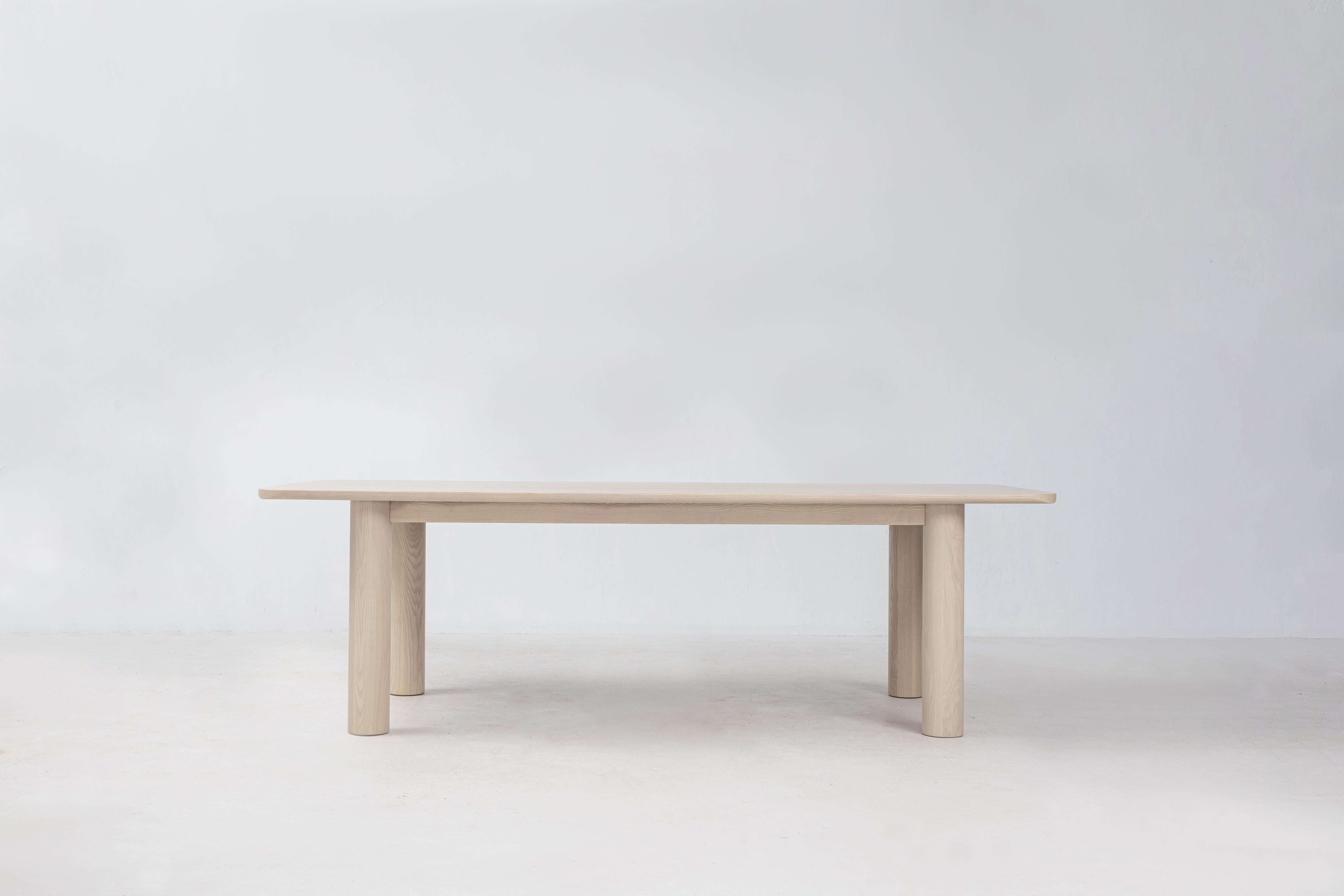 La table à manger Arc est fabriquée en frêne blanc américain FSC® massif. Ce centre de table est destiné à vivre autour de la table à manger et présente de magnifiques détails d'angle avec de larges pieds cylindriques. Veuillez noter que nous