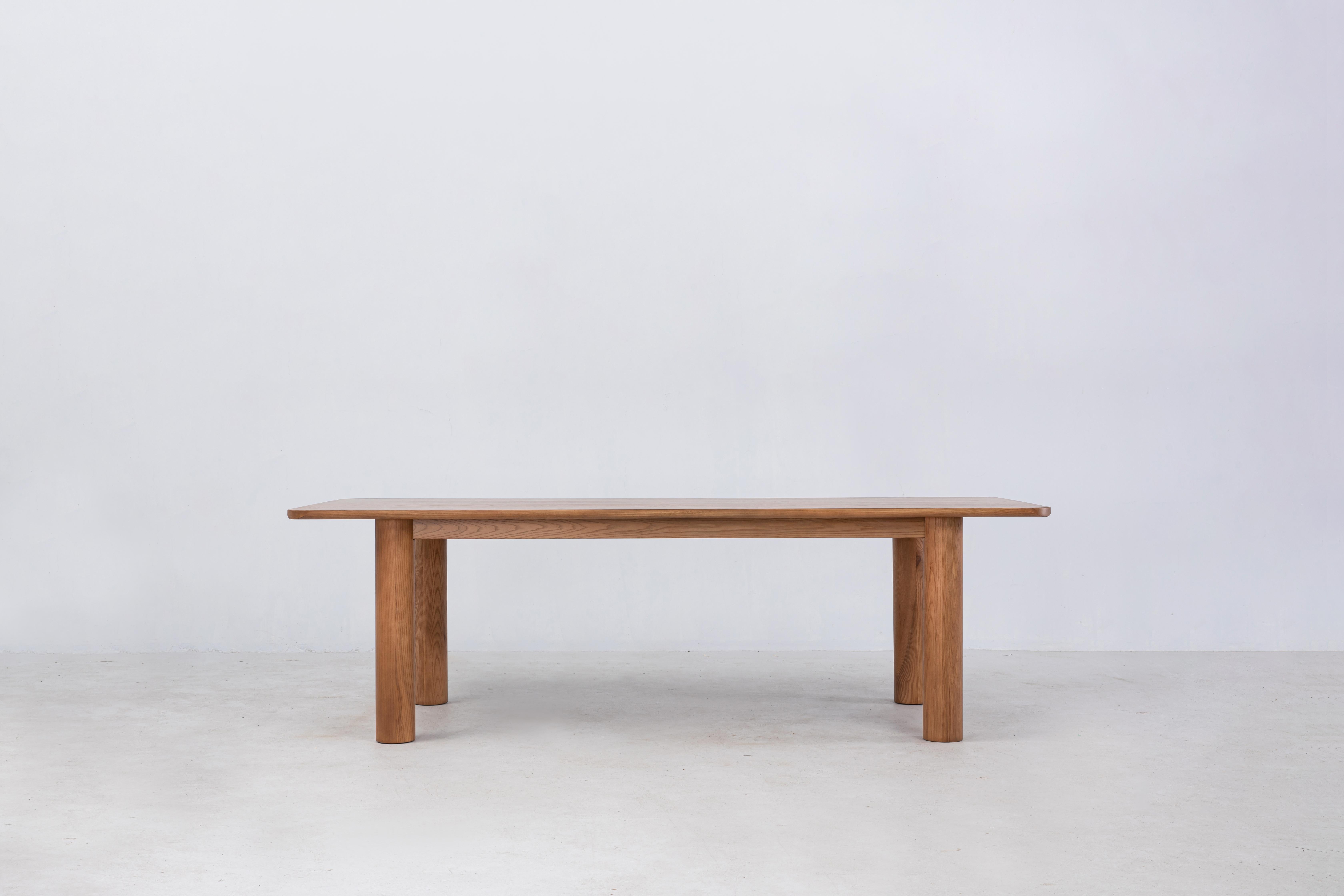 La table à manger Arc est fabriquée en frêne blanc américain FSC® massif. Ce centre de table est destiné à vivre autour de la table à manger et présente de magnifiques détails d'angle avec de larges pieds cylindriques. Veuillez noter que nous