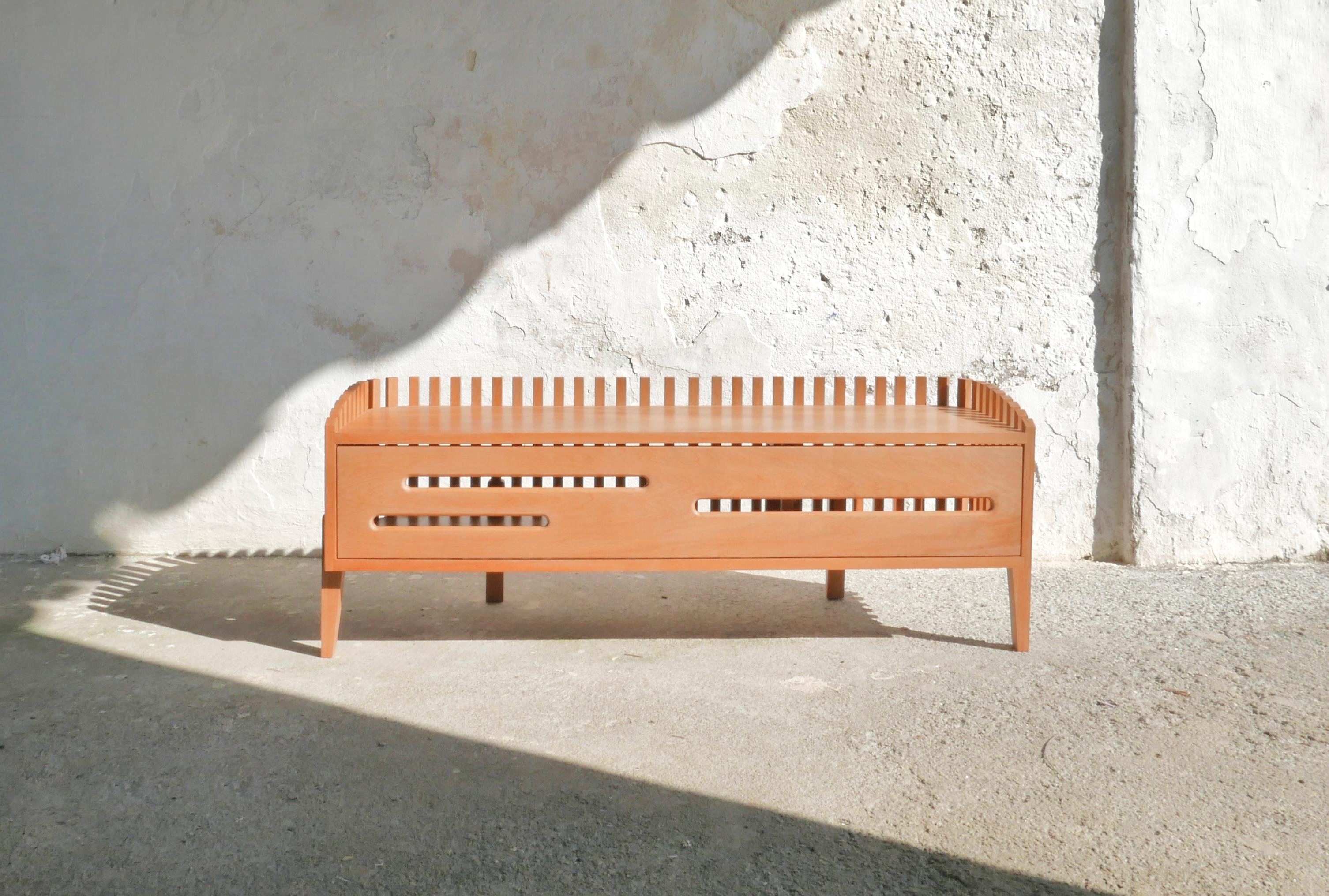 Die Arca Schuhablage/Bank besteht aus dünnen Holzlatten, die das Möbelstück umschließen, den Hauptkörper stützen und ein Gefühl der Bewegung erzeugen. Die Lamellen ermöglichen eine ständige Belüftung und schaffen gleichzeitig einen geschlossenen