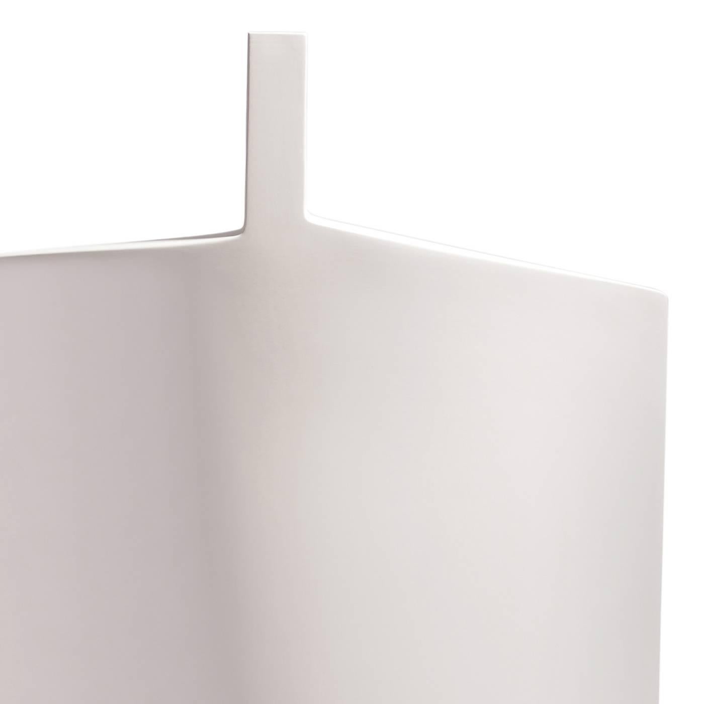 This elegant vase in ceramic was hand-painted in white and features a modern silhouette that mixes smooth texture, a sinuous front profile, and sharp angles that make the shape of its top and neck. Traditional techniques and materials coexist with