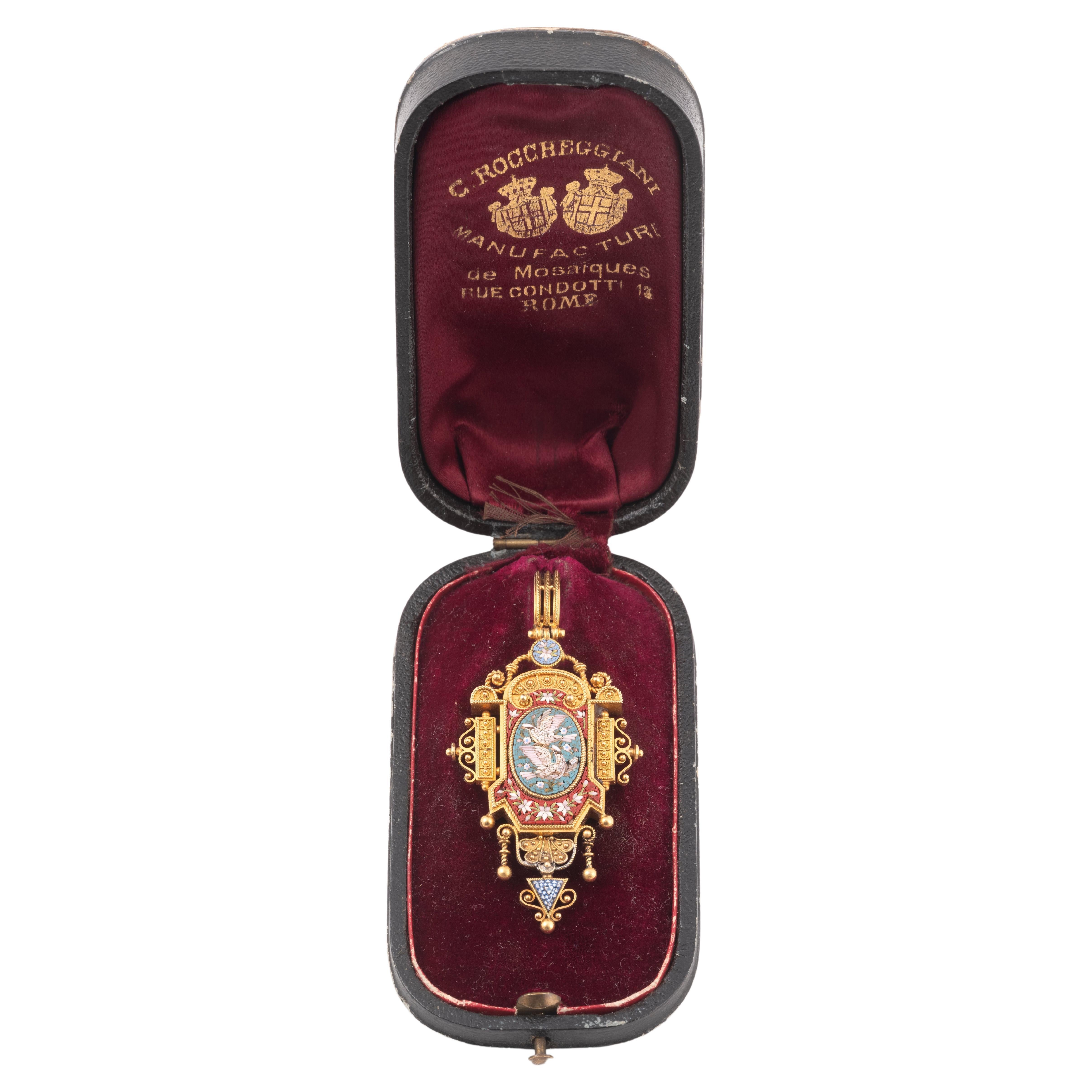 Cesare ROCCHEGGIANI (active from 1856 to 1864)
18kt Yellow gold pendant set with a micromosaic medallion depicting a pair of doves on a blue background, surrounded by garlands of flowers, seeds and gold beads in the Etruscan style.
Italian work,