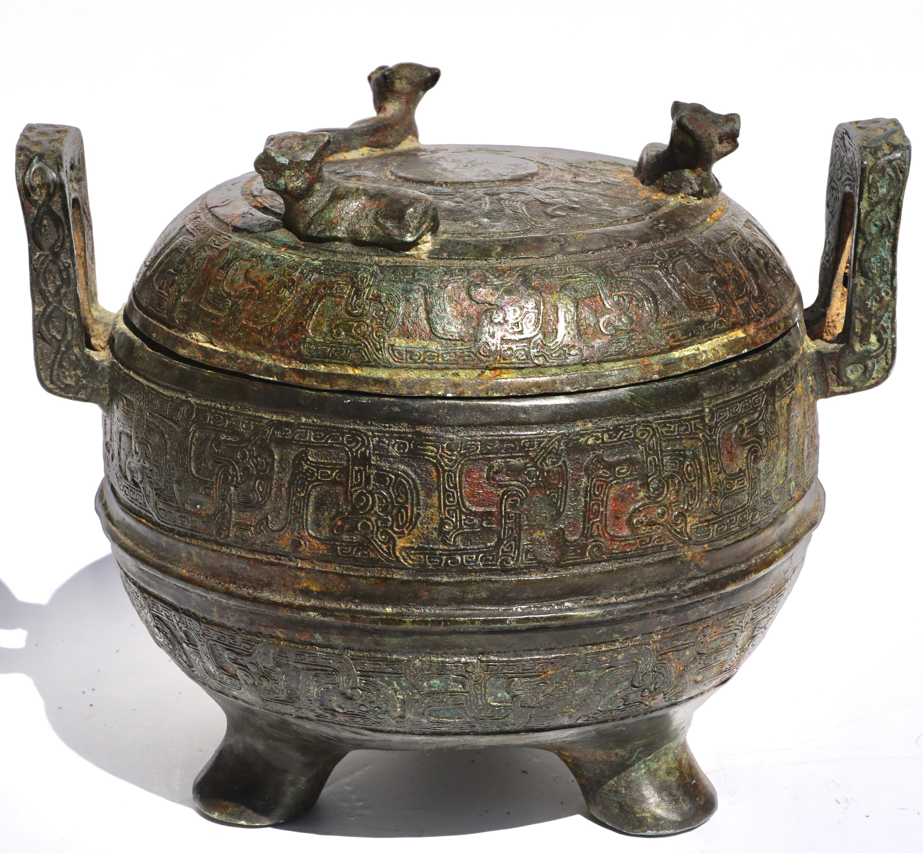 Chinese Bronze Archaistic Warring States Period Ding Pot. Circa 500 BCE

A beautifully shaped medium size bronze ritual vessel with three elegant feet and a lid with three bovine figures. The pot with two handles is decorated from top to bottom with