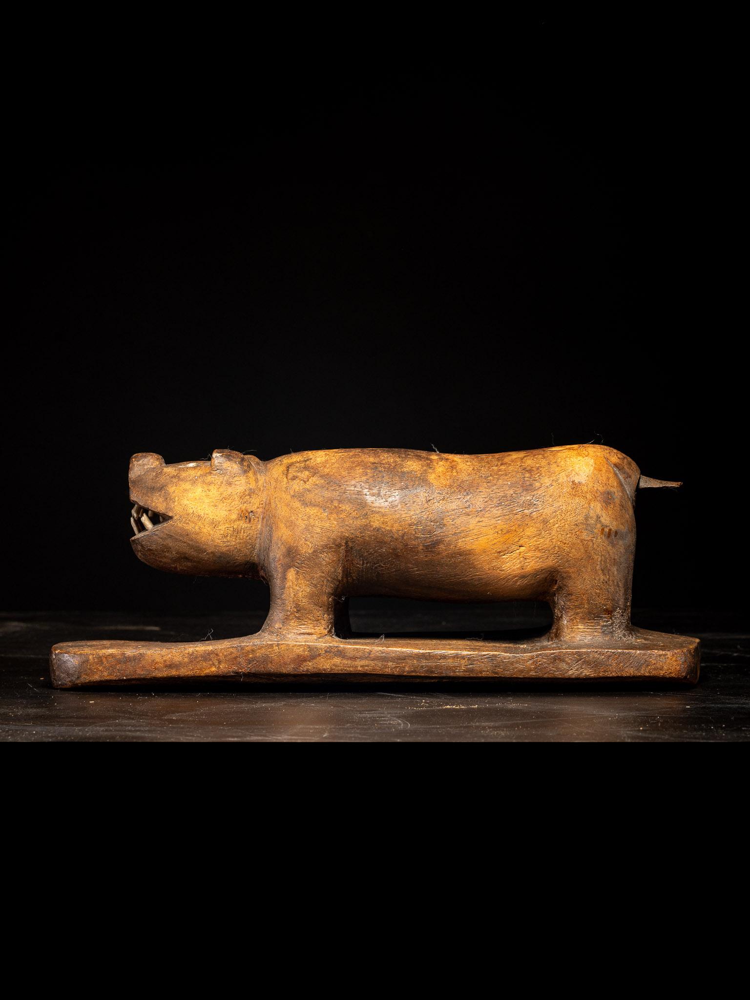 Una escultura de oso hecha a mano por los esquimales de Alaska, con dientes de hueso y una base de madera maciza. Su pátina y su base indican que pudo estar unida a un kayak de caza.