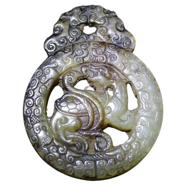 Dimensioni e peso 

4.4 x 5.8 x 0.7 cm 

31.6 grammi

Questo ciondolo arcaico in giada presenta una mitica tartaruga con un serpente al centro, circondata da un anello con un motivo a nuvole. Sulla parte superiore ci sono due chilong simmetrici che