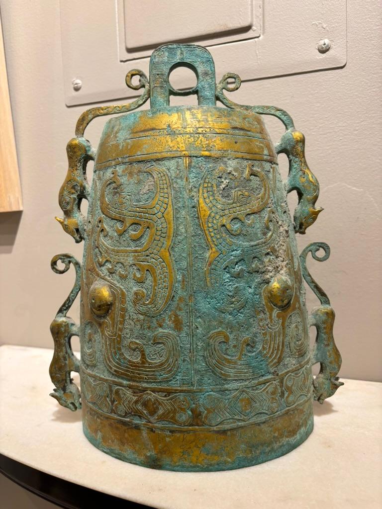 Campana rituale arcaica cinese in bronzo dorato con pantere in rilievo sui lati, una maschera stilizzata sulla parte anteriore e posteriore, decorazioni geometriche incise e a rilievo. Con una meravigliosa patina verdastra. Con un'altezza di 14,5