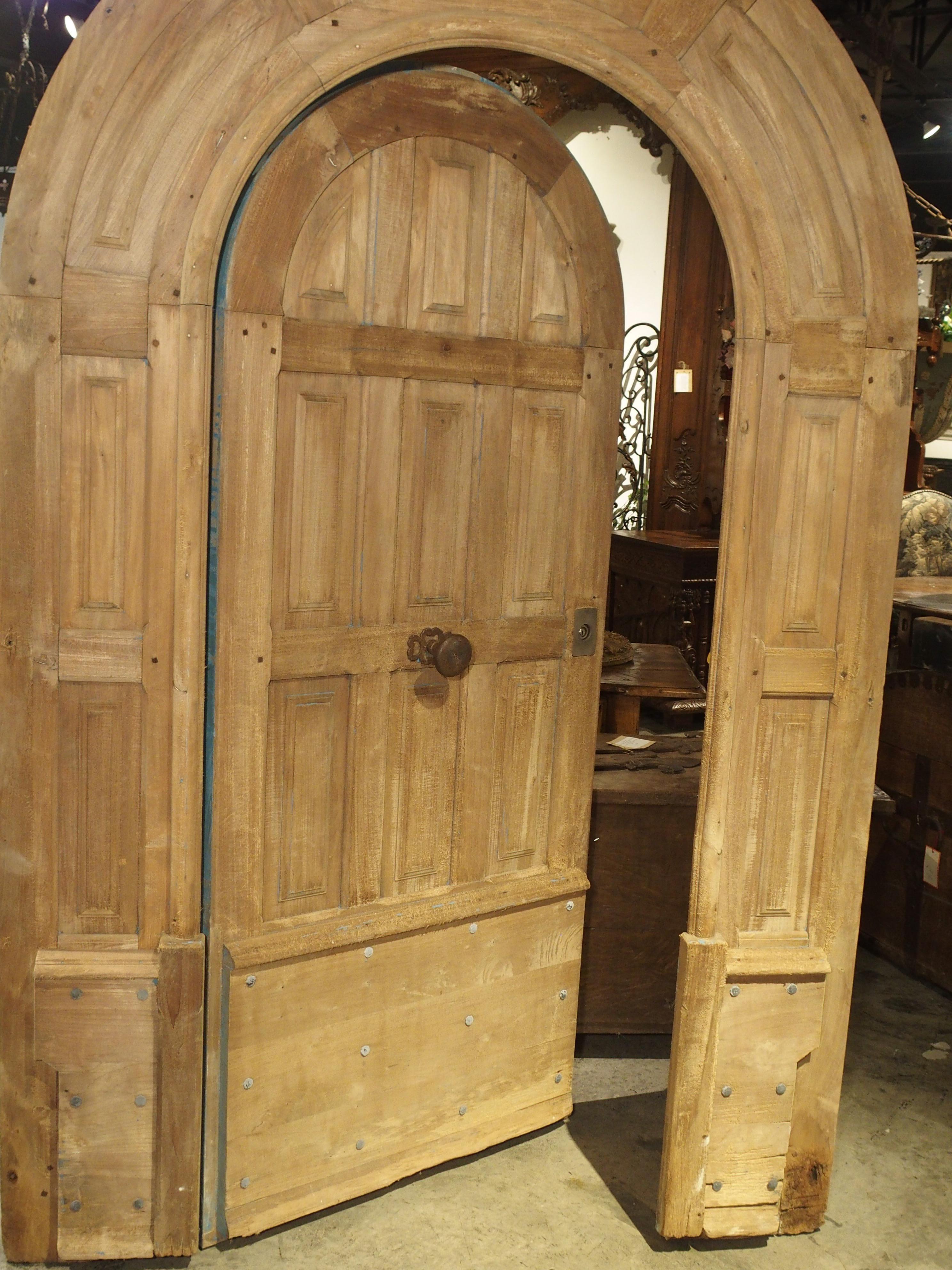From France, this amazing arched entry door is made from stripped French oak. The door is still attached to its original arched surround, and the decoration consists of simple, triple raised panel moldings going down three quarters of the door. The