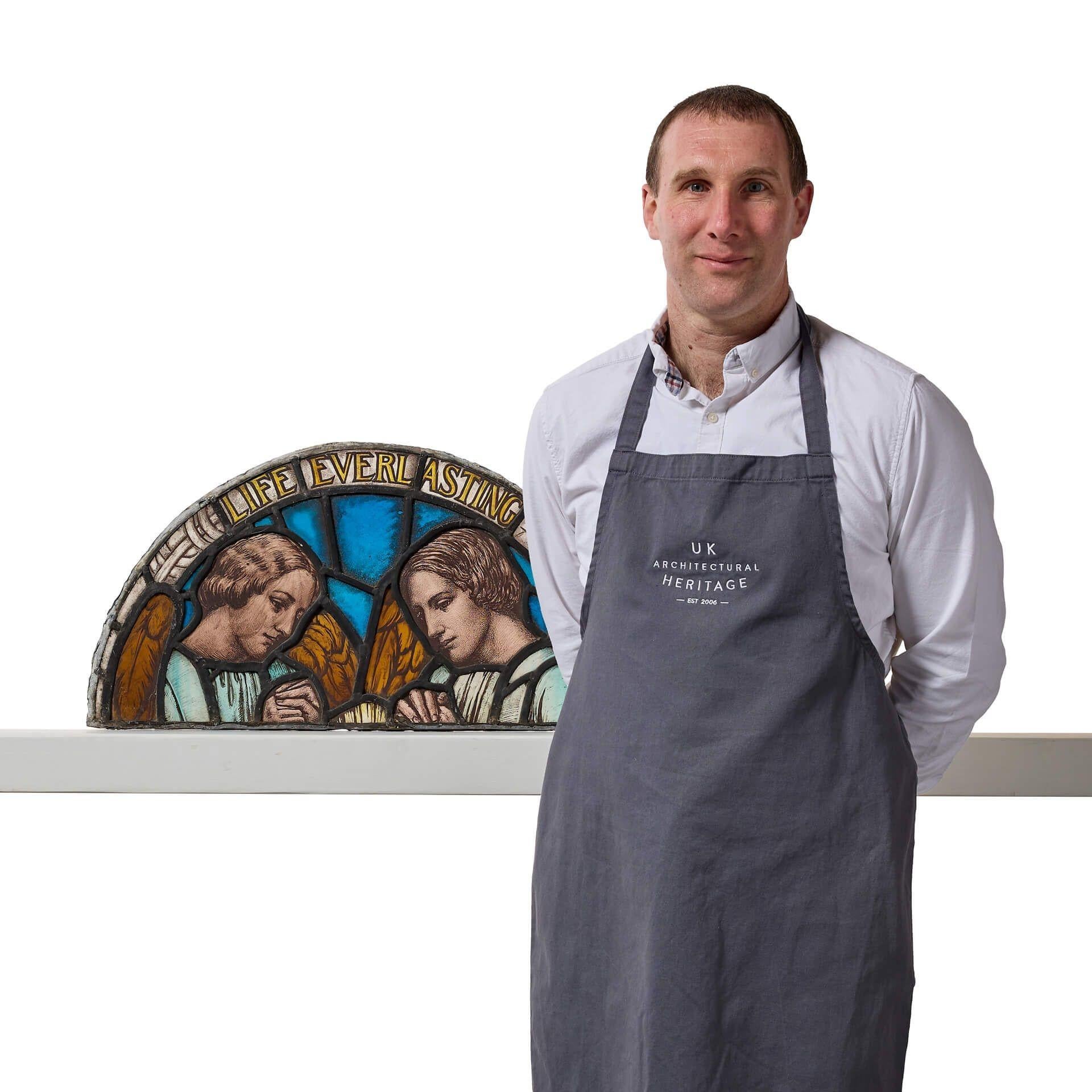 An early 20th century arched antique religious stained glass window depicting two angels at prayer below the words ‘Life Everlasting’.

Reclaimed from an English church, this semi-circular stained glass panel tells the story of a once larger