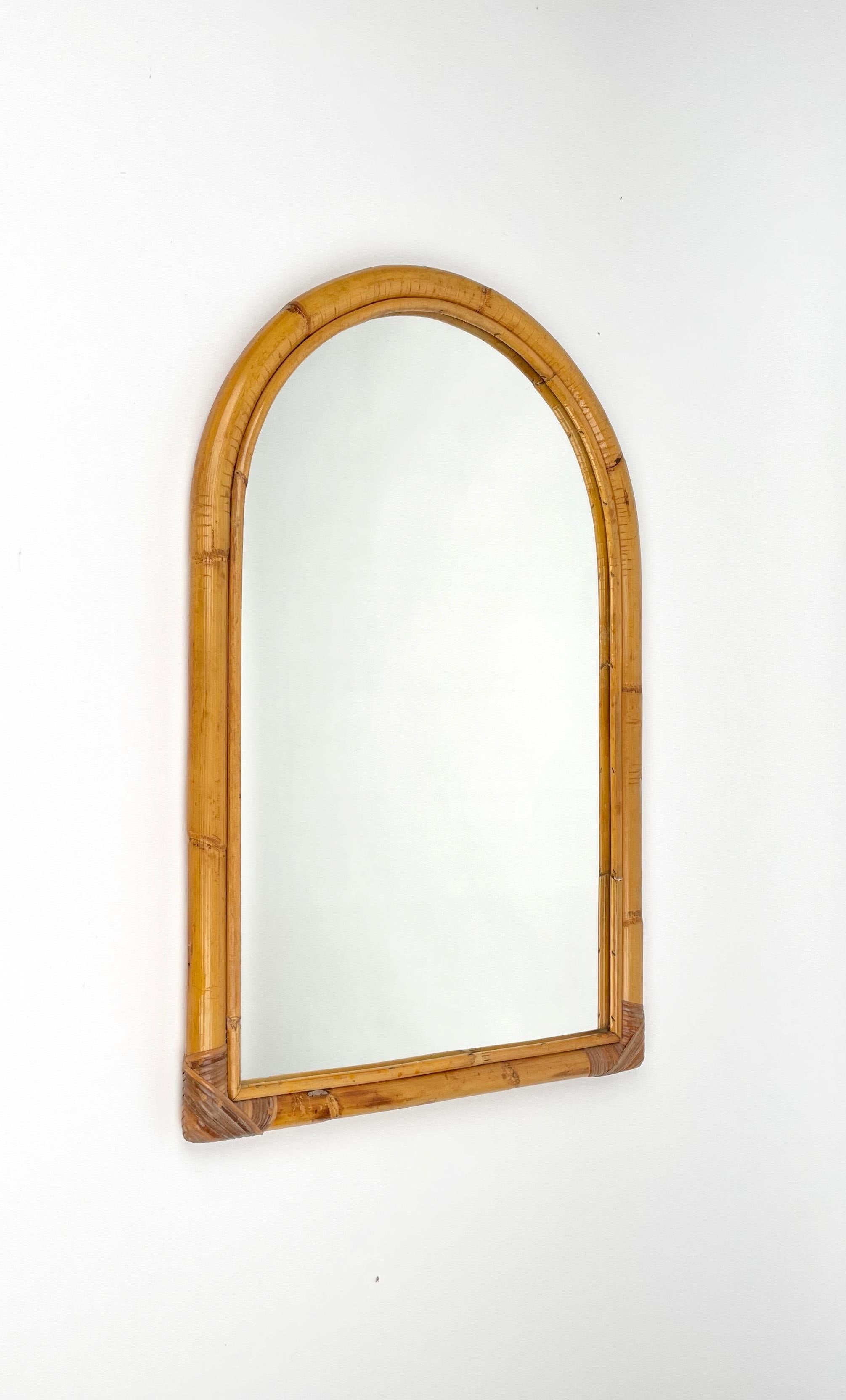 Arched wall mirror framed with bamboo and rattan. 

Made in Italy in the 1970s.