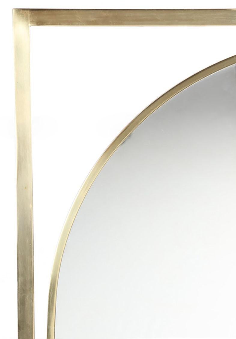 Uncommon large brushed brass square stock framed mirror floating inside a brushed brass square stock open frame, possibly midcentury Italian. The arched mirror is supported inside the rectangular brass frame by a series of brass cuffs.