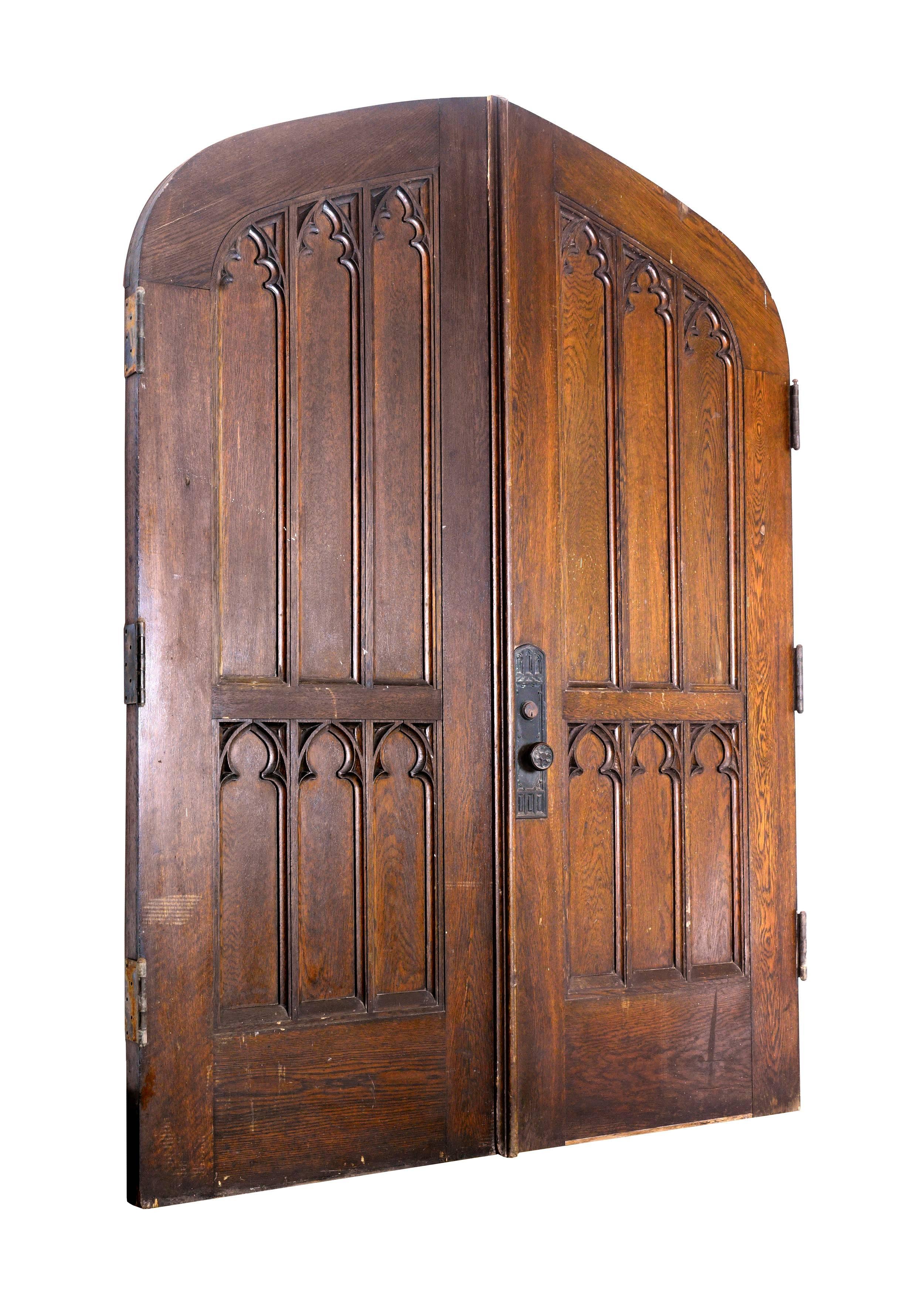Stunning set of thick oak Gothic double doors with impeccably matching hardware. A low and wide depressed arch accents the elongated recessed panels adorned with trifoil designs. At nearly 3” thick, these doors are solid and built to last. Perfect