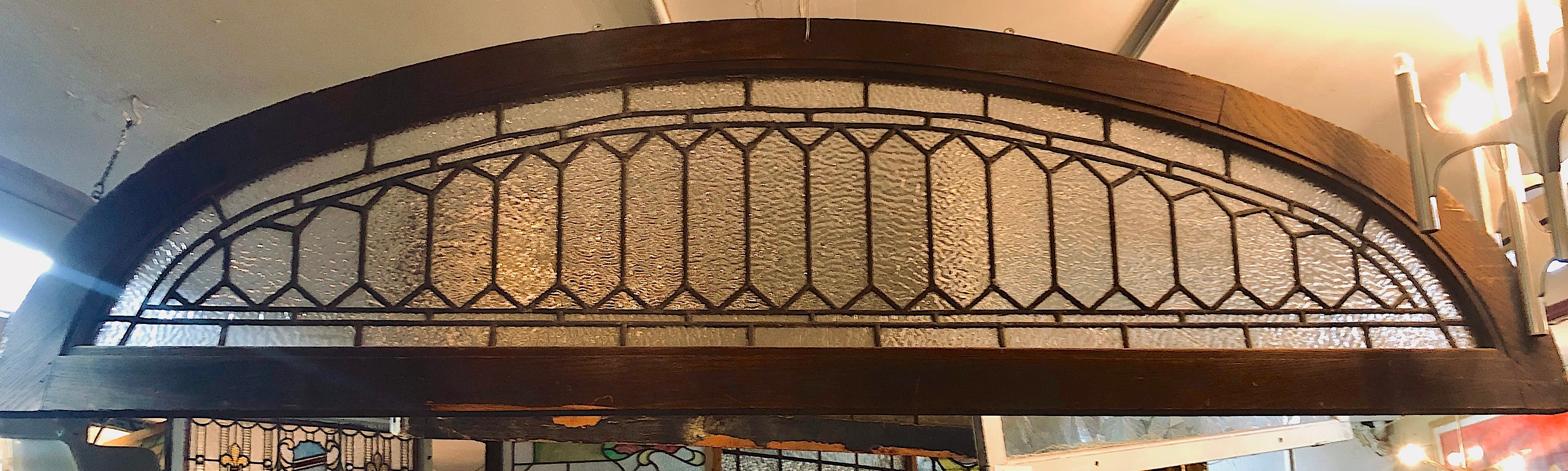 Fenêtre en arc long avec un design plombé et un verre texturé. D'une longueur de plus de deux mètres, cette pièce architecturale vous apportera une grande luminosité.
Le vitrail est actuellement placé dans un cadre temporaire en bois - les
