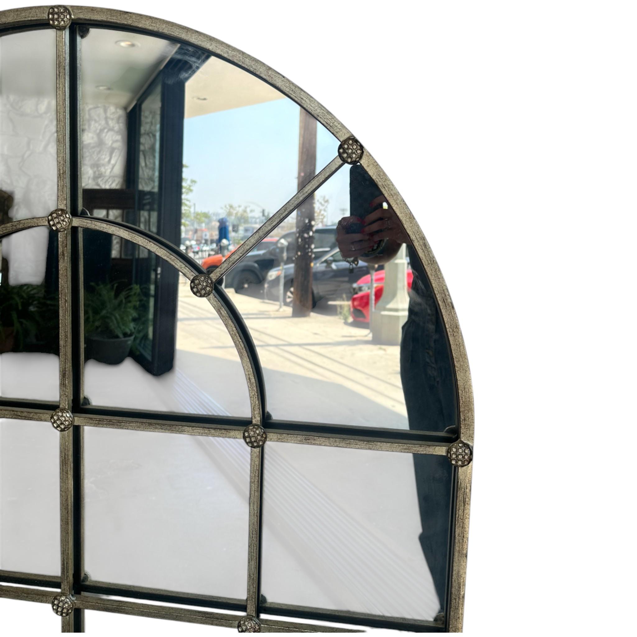 Un llamativo espejo arqueado con atractivo industrial vintage, esta pieza presenta una rejilla segmentada enmarcada en metal envejecido con detalles de roseta en cada intersección. El espejo evoca la sensación de los antiguos cristales de ventana,