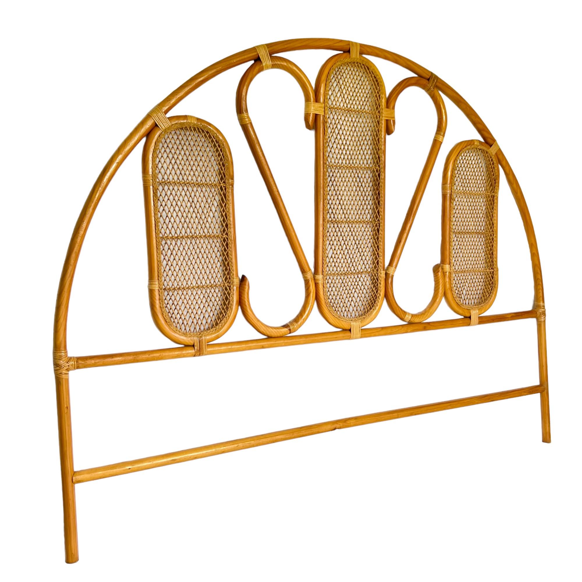 A vintage Palm Beach regency rattan and pencil reed arched king headboard. The open design features a bentwood frame with scrolled details and three oval woven panels trimmed with braided wicker.

Dimensions: 81
