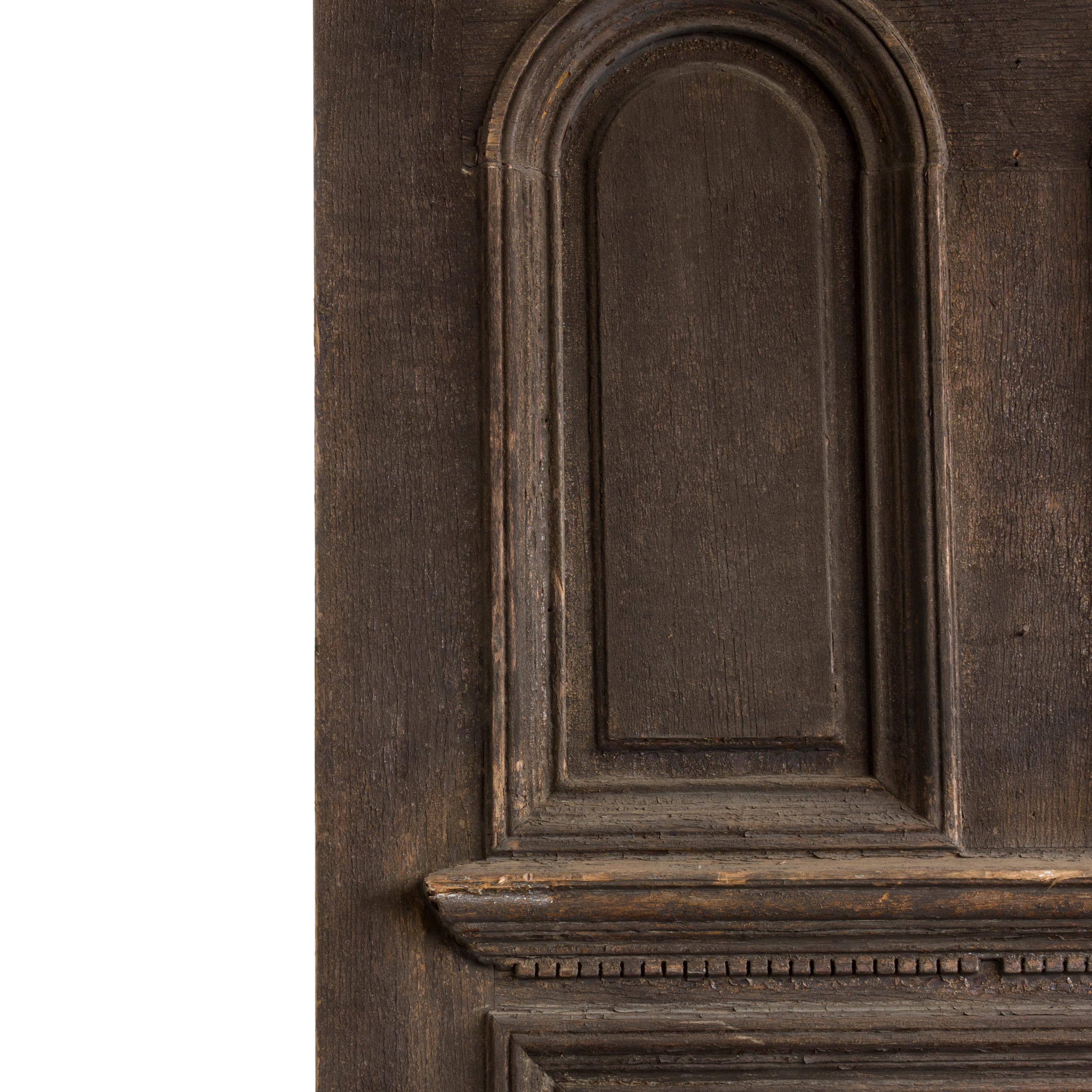 This solid and heavy solid oak door has great architectural accents. Deep recessed panelling and a dentiled cornice ledge create a visually imposing door with beautiful antique character. Salvaged from a church in New England.