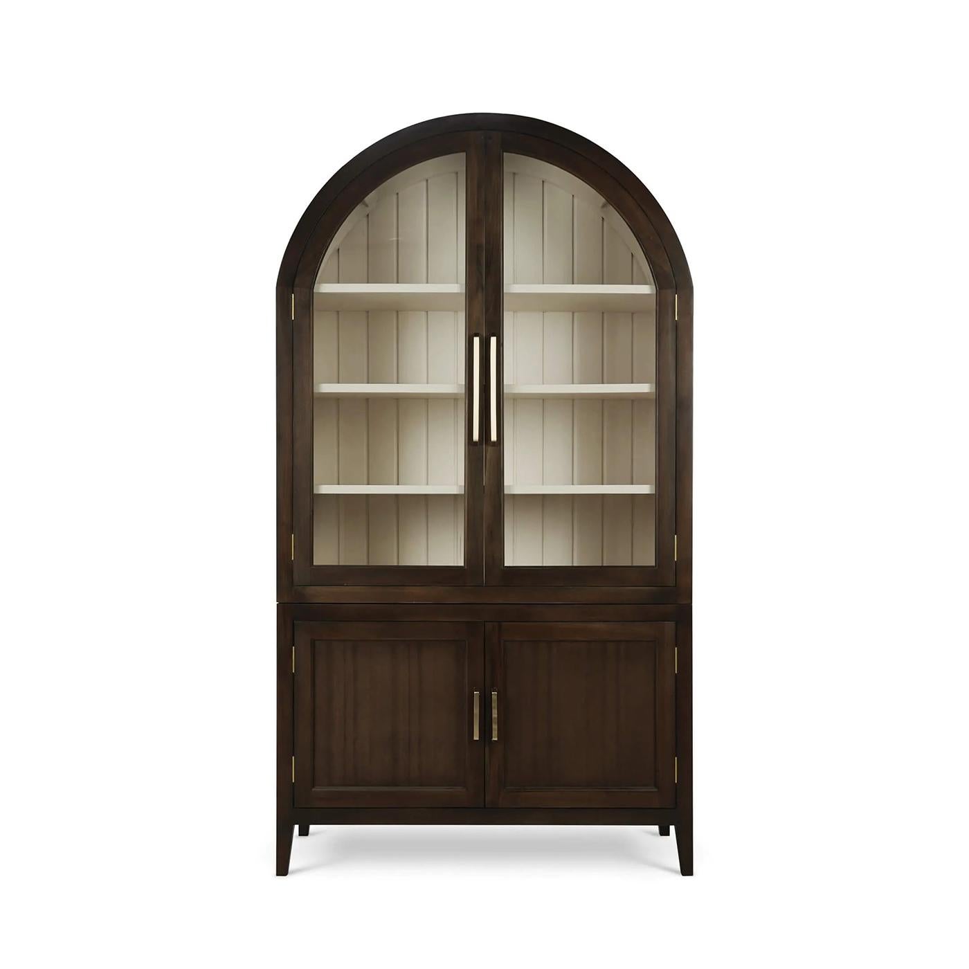 Finished in a rich walnut tone, this tall display cabinet features a gracefully curved top, glass-paneled doors, and an airy interior painted in a soft putty hue. Four interior shelves provide ample space for showcasing fine china, glassware, or