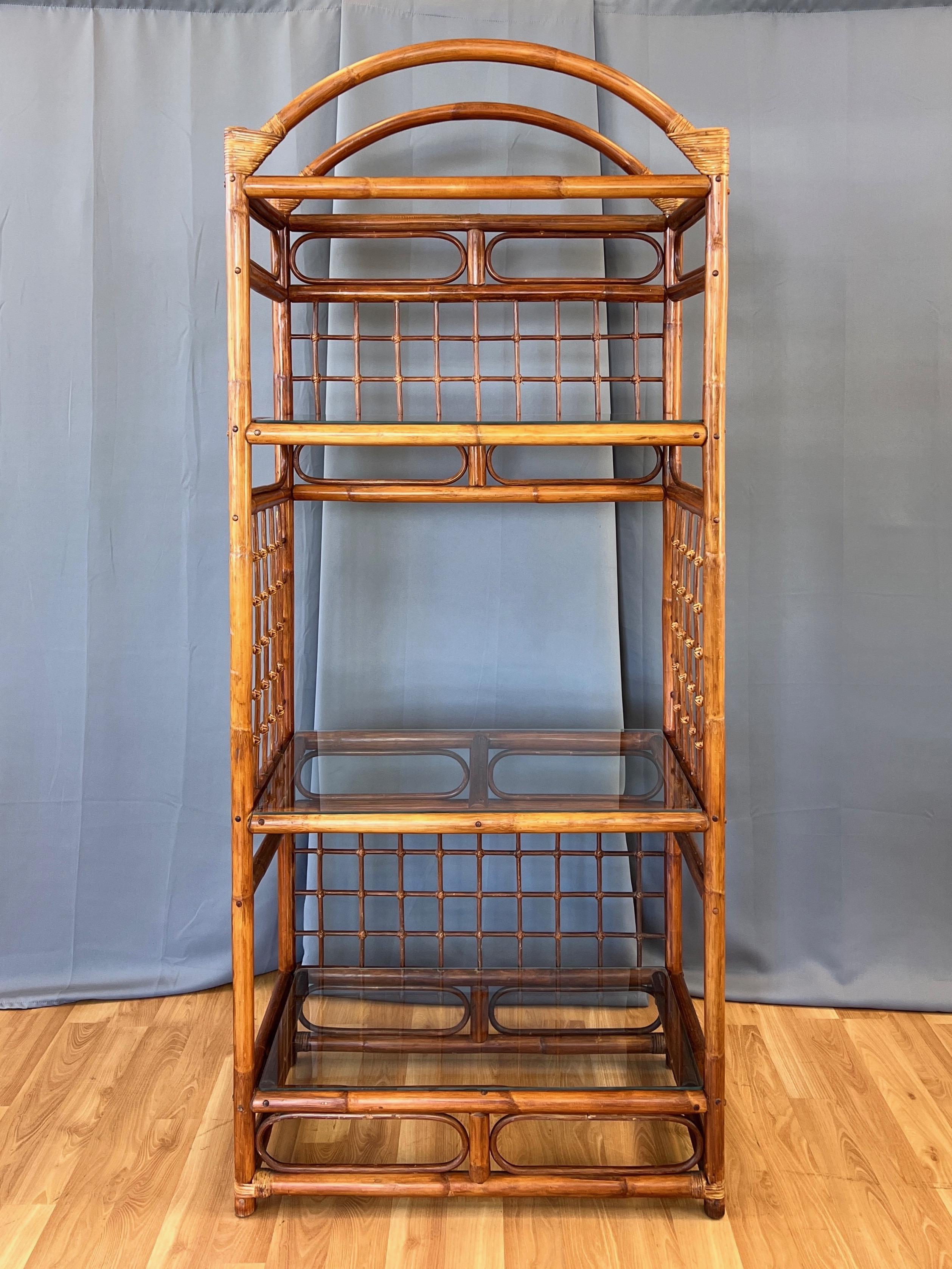 A tall and spacious 1970s bent rattan étagère or shelving unit with three glass shelves.

Arched top with various bent rattan elements and woven lattice panels at back and sides. Corners and lattice feature wrapped and woven cane details. Finished