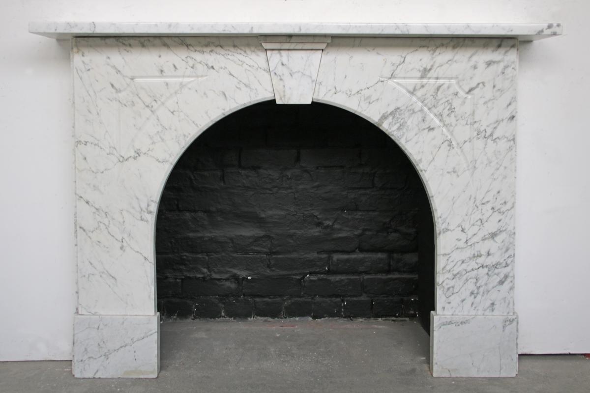 An arched Victorian Carrara marble fireplace surround of simple form. Circa 1860. The two arched jambs are picked out with fluted detail and meet at a simple unadorned keystone.

For detailed sizes please see the size diagram in the image gallery.