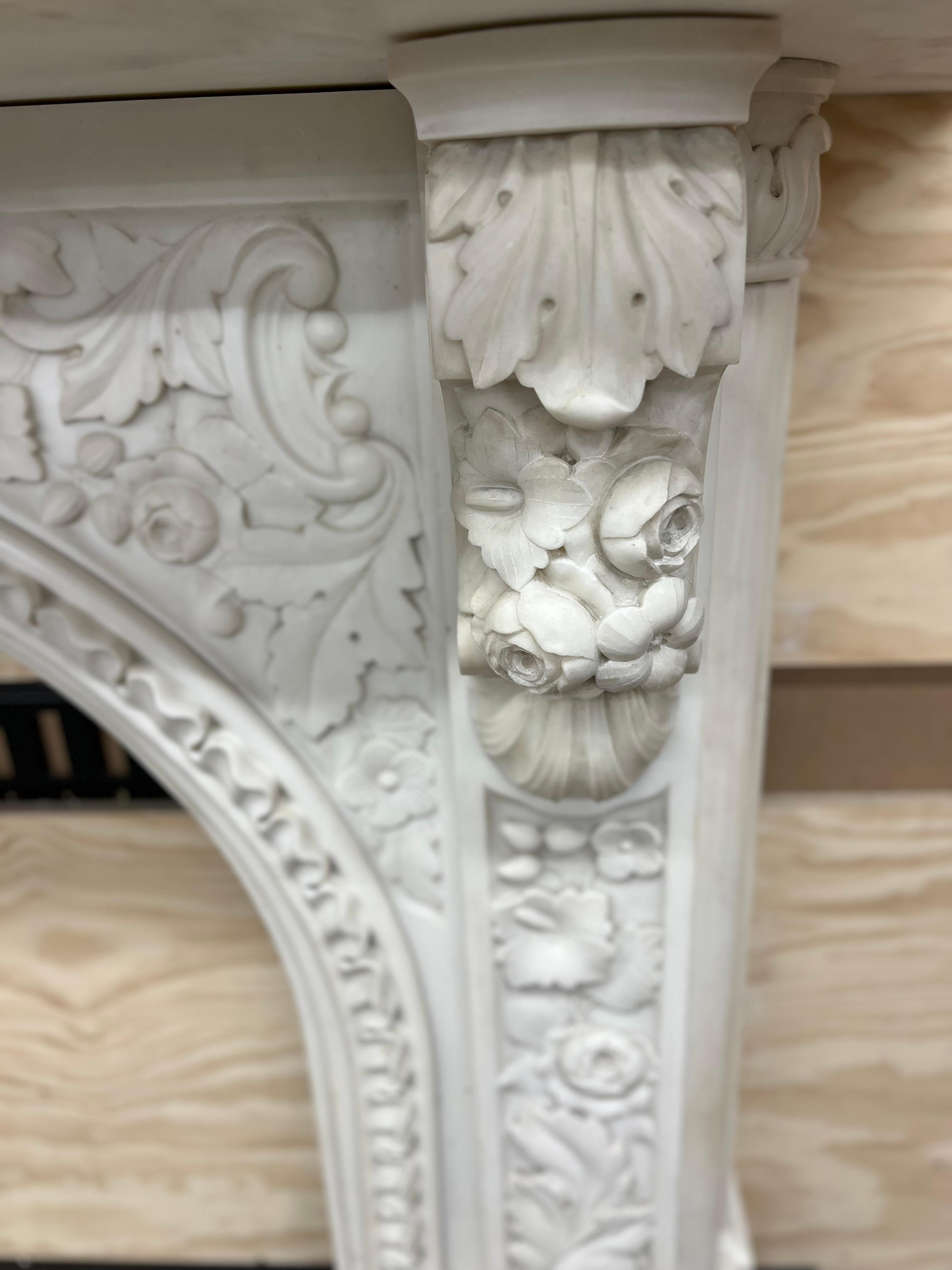 Cheminée victorienne arquée vers 1860, sculptée en marbre Statuaire, avec une ouverture de foyer conçue pour accueillir une grille de registre, avec une sculpture de feuillage abondante sur les panneaux de jambage et de frise, répétée dans les