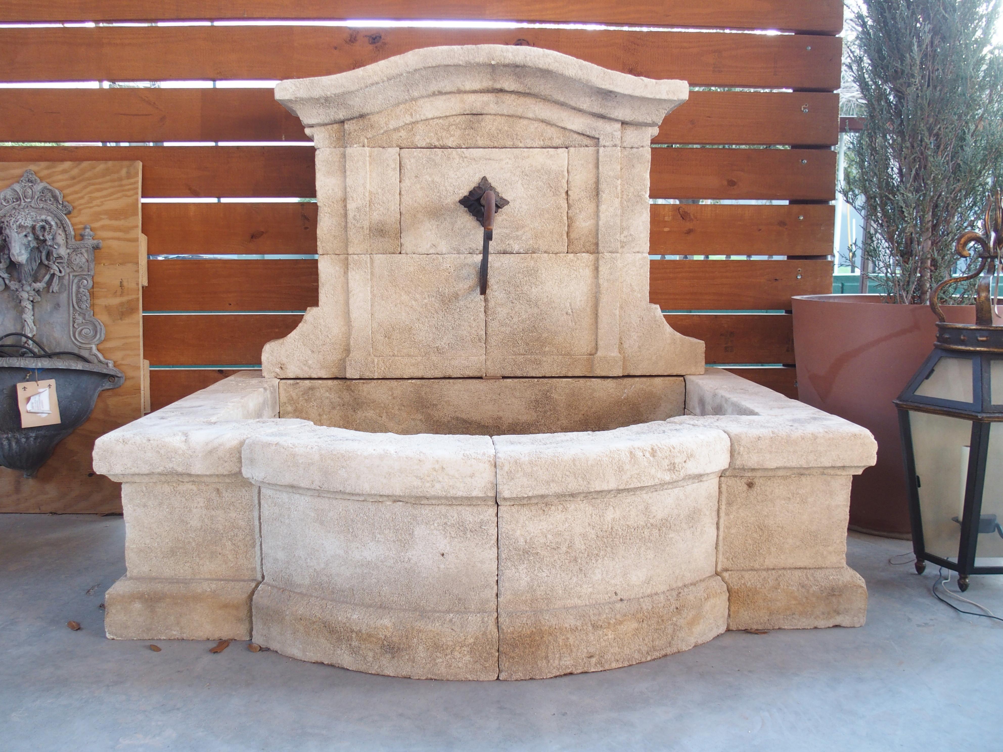 Dieser französische Wandbrunnen wurde in der Provence von Hand aus Kalkstein gemeißelt und hat eine gewölbte Rückseite mit einem ähnlichen Becken in Form eines Chapeaus. Jedes der 19 Stücke aus Estaillade-Kalkstein hat eine cremefarbene Farbe mit
