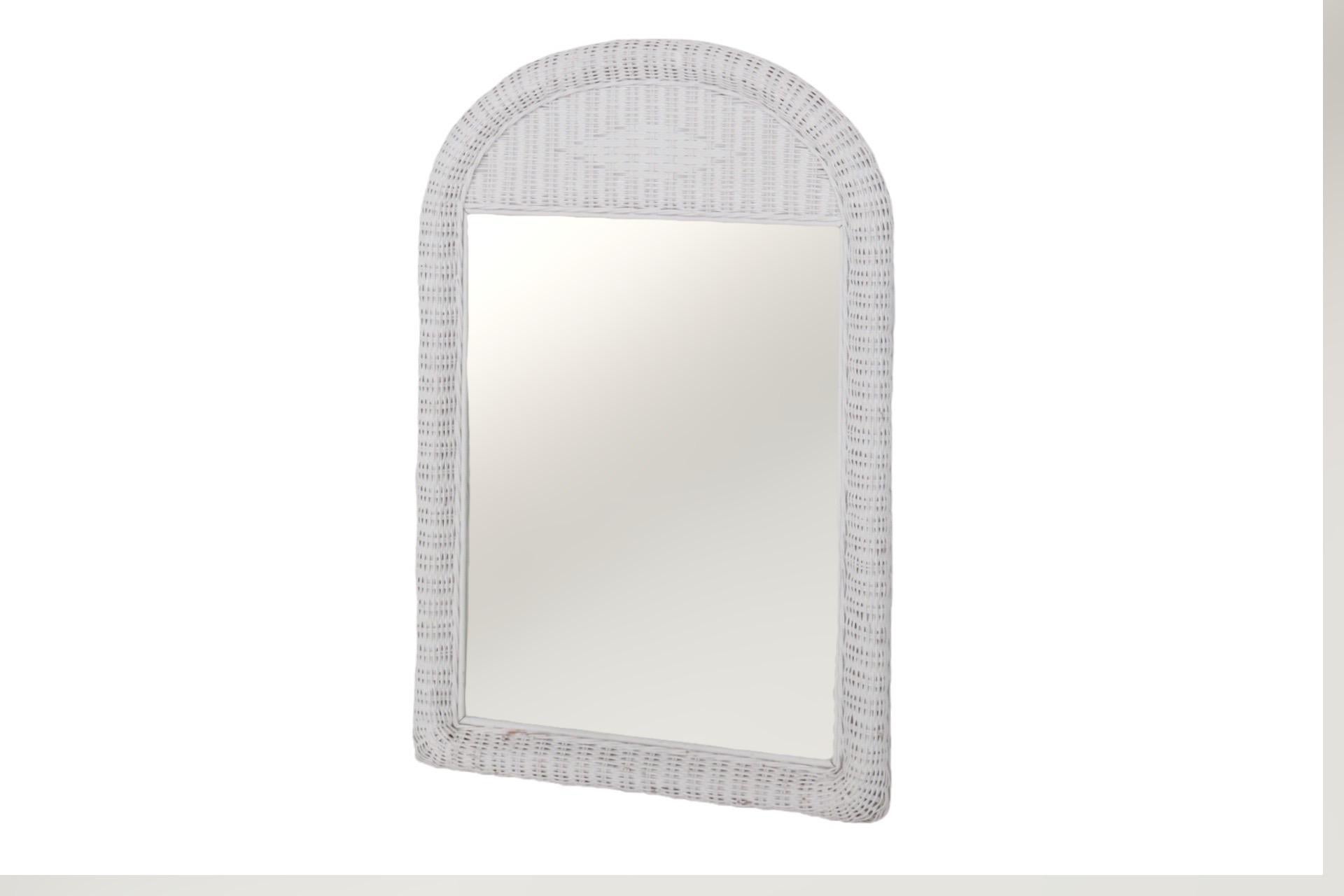 A rectangular mirror in an arched white wicker frame, finished with a pencilwood bamboo interior edge.
 