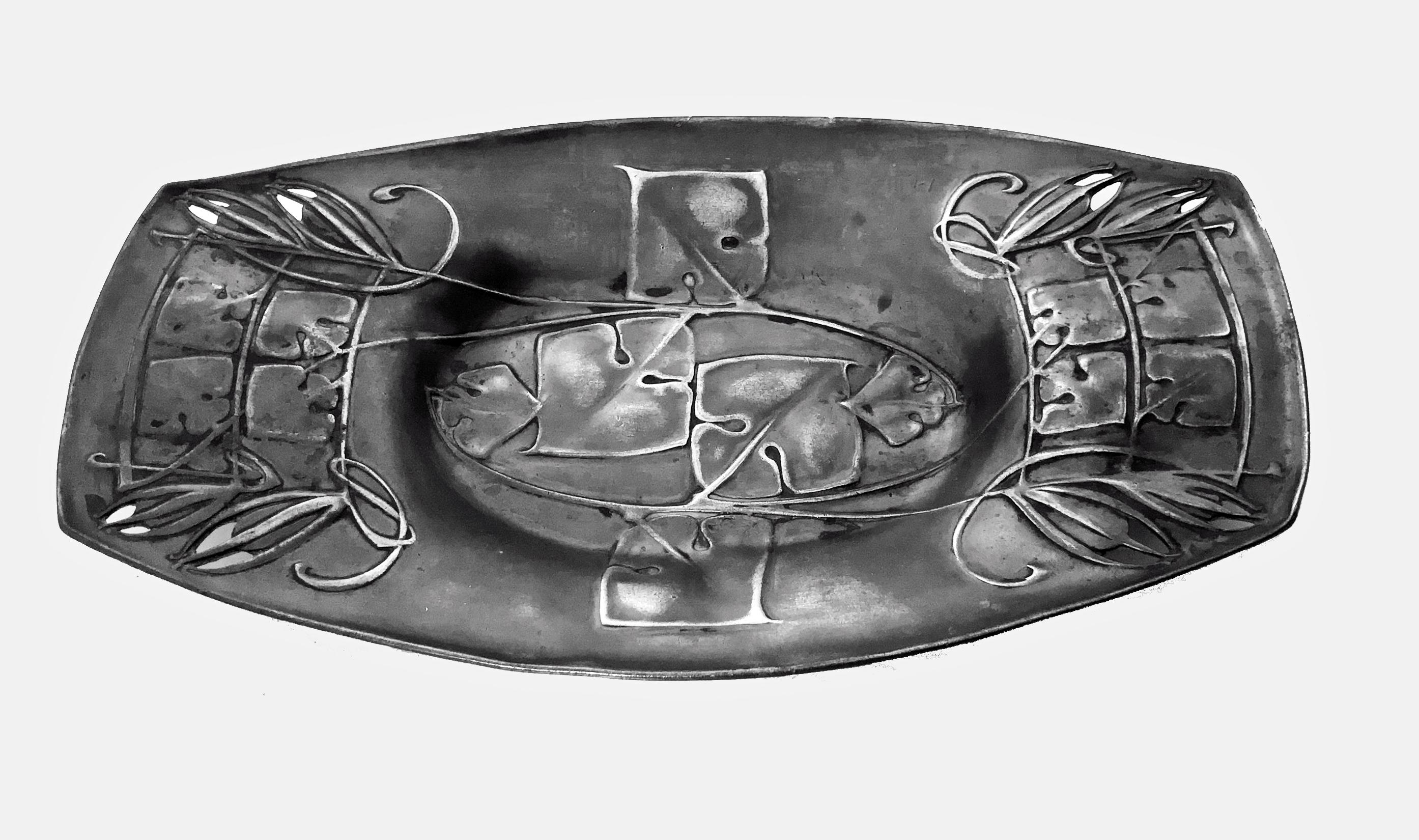 Archibald Knox pour Liberty & Co. Plateau à gâteau ou à dessert en étain Arts & Crafts, vers 1904. Les côtés légèrement incurvés et le centre ovale en retrait, tous avec des feuilles et des fleurs stylisées. Estampillé sur le dessous English Pewter