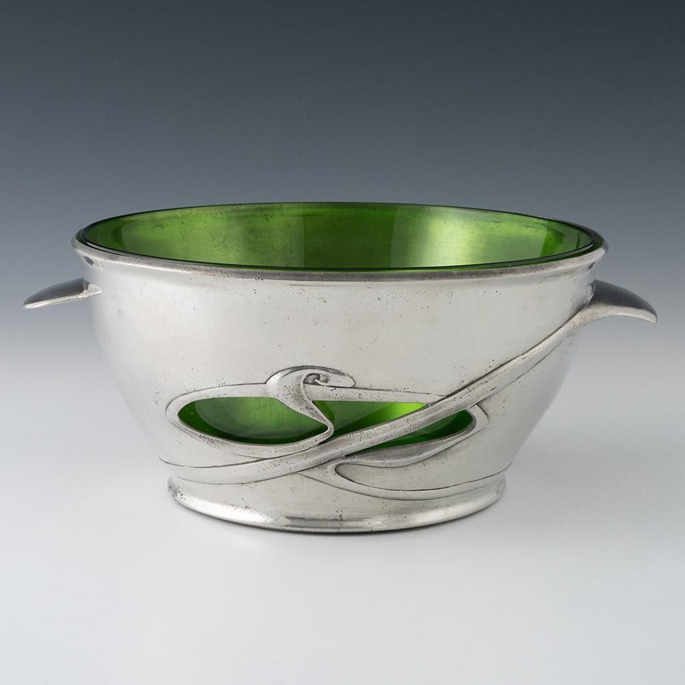 Encabezado: diseño de Archibald Knox para el centro de peltre Liberty & Co Tudric
Fecha : c1905. Marcado Tubric 0318 con Rd 427517
Periodo : Eduardo VII
Origen : W. H. Haseler, Birmingham, Inglaterra. Vidrio de James Powell
Decoración : Dos
