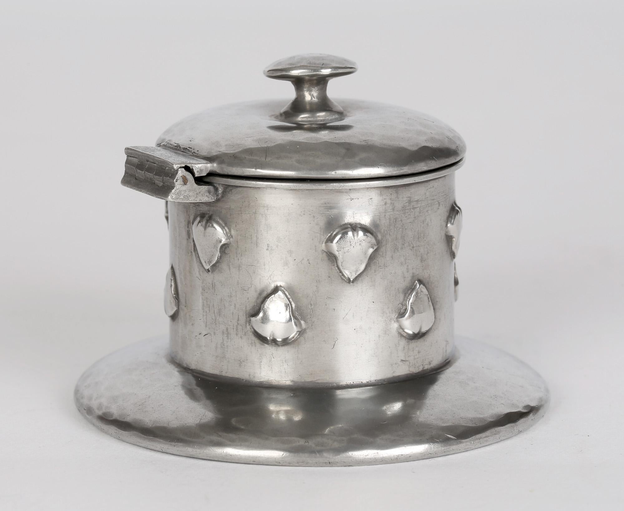 Stylish Art Nouveau Tudric planished pewter inkwell mad for Liberty & Co design attributed to Archibald Knox (Scottish, 1864-1933) and dating from around 1905. The inkwell stands raised on a wide rounded base with a cylindrical body with small