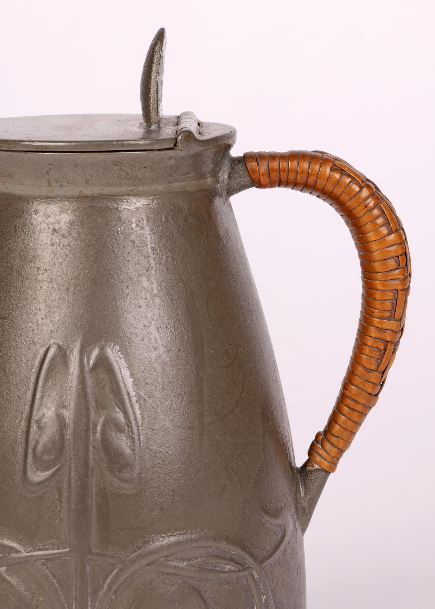 A stylish art nouveau Tudric pewter jug molded with stylized floral designs by renowned designer Archibald Knox (British, 1864-1933) and dating from around 1905. 

Many of these pieces were made and retailed through Liberty & Co, London with Knox