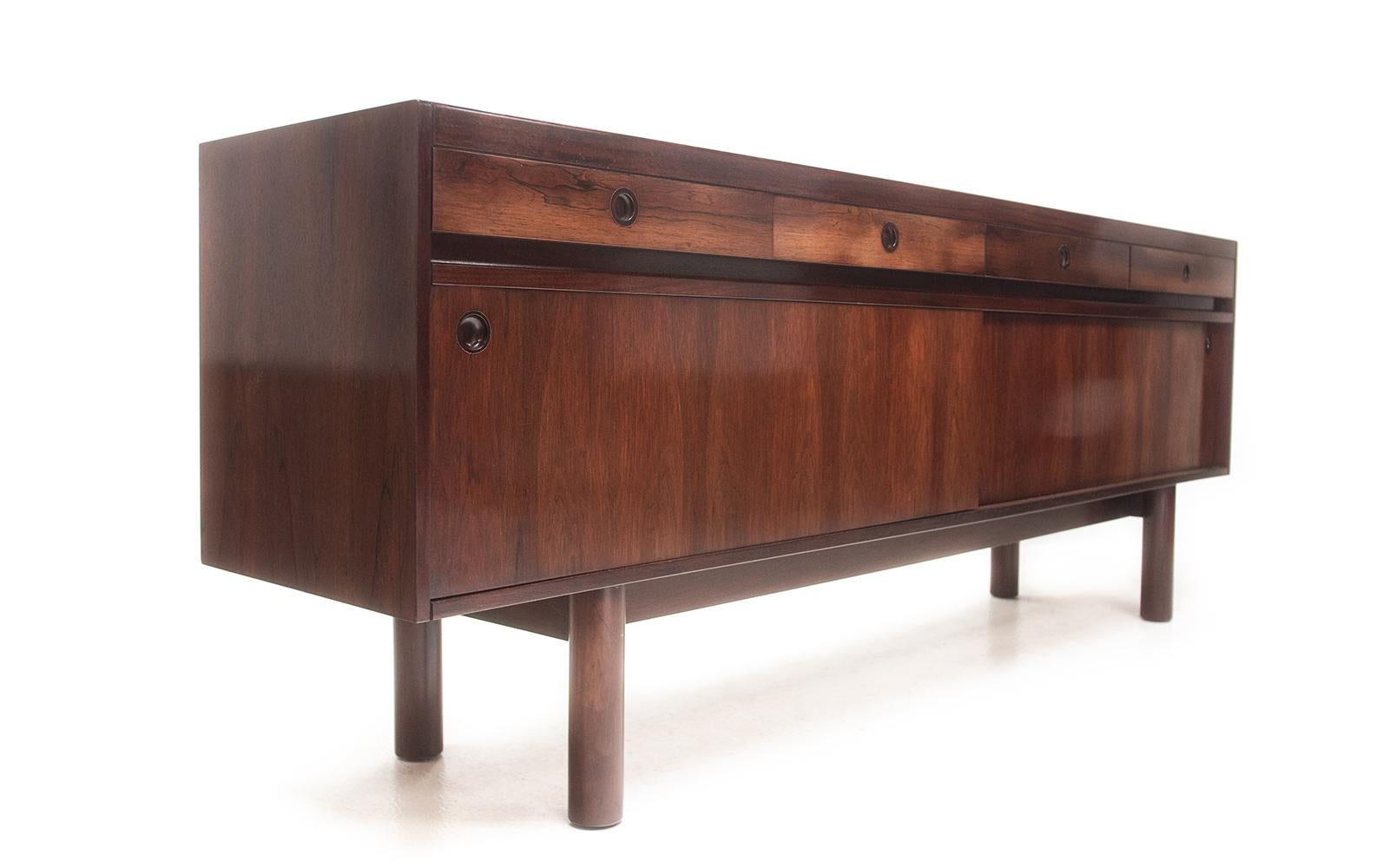 Archie Shine sideboard 

British mid-century Archie Shine and Robert Heritage for Heal's Sideboard.

This sleek rosewood sideboard has four shallow drawers, each with recessed handles over sliding door storage. 

Original paper label to inner