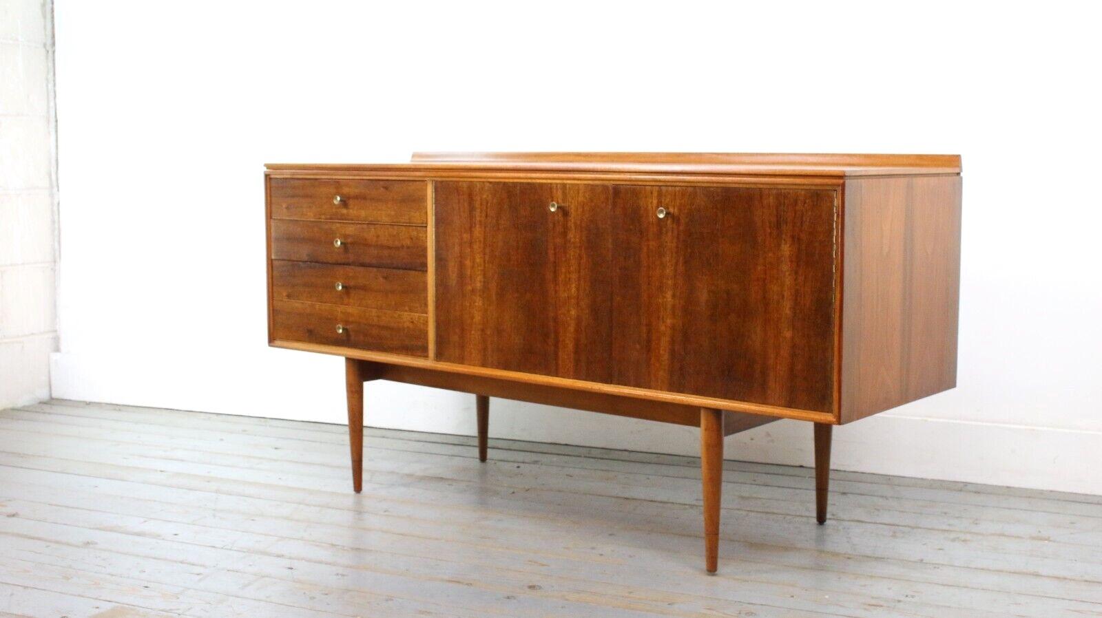 Archie Shine Sideboard by Robert Heritage with a rich grained Indian Laurel front.

This rarely available compact design with brass trumpet-shaped handles is a sought-after Archie Shine' Hanover' sideboard. Featuring four drawers and a shelved