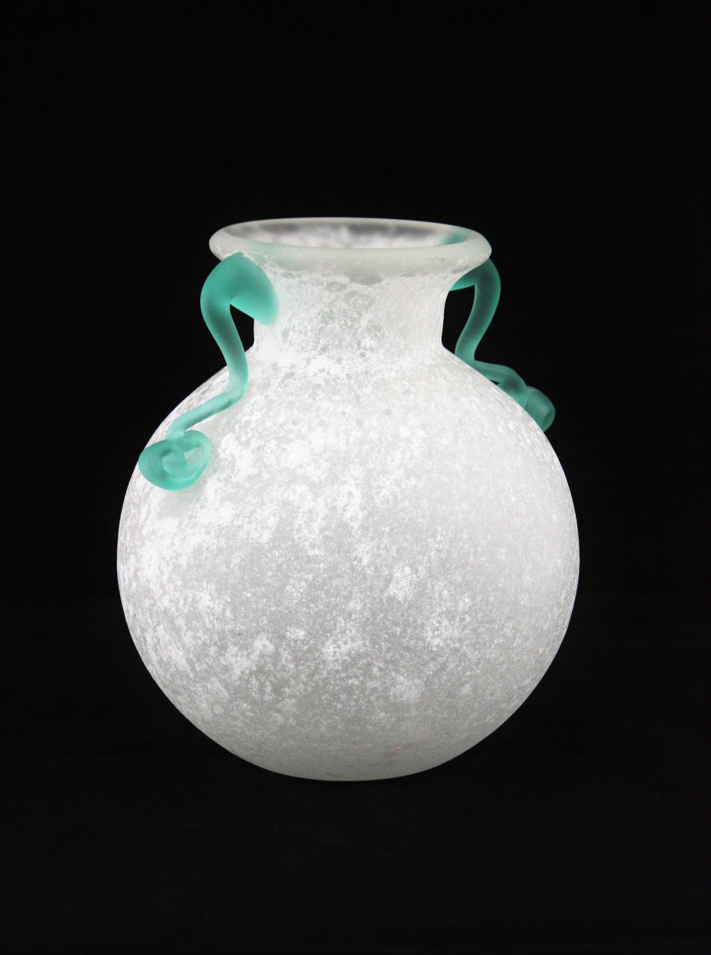 Hand blown Murano glass scavo bianco corroso vase in white color with applied green handles. Attributed to Archimede Seguso and Seguso Vetri d’Arte, Italy, 1960s.
This eye-catching Murano glass bottle vase is made with frosted white glass using the