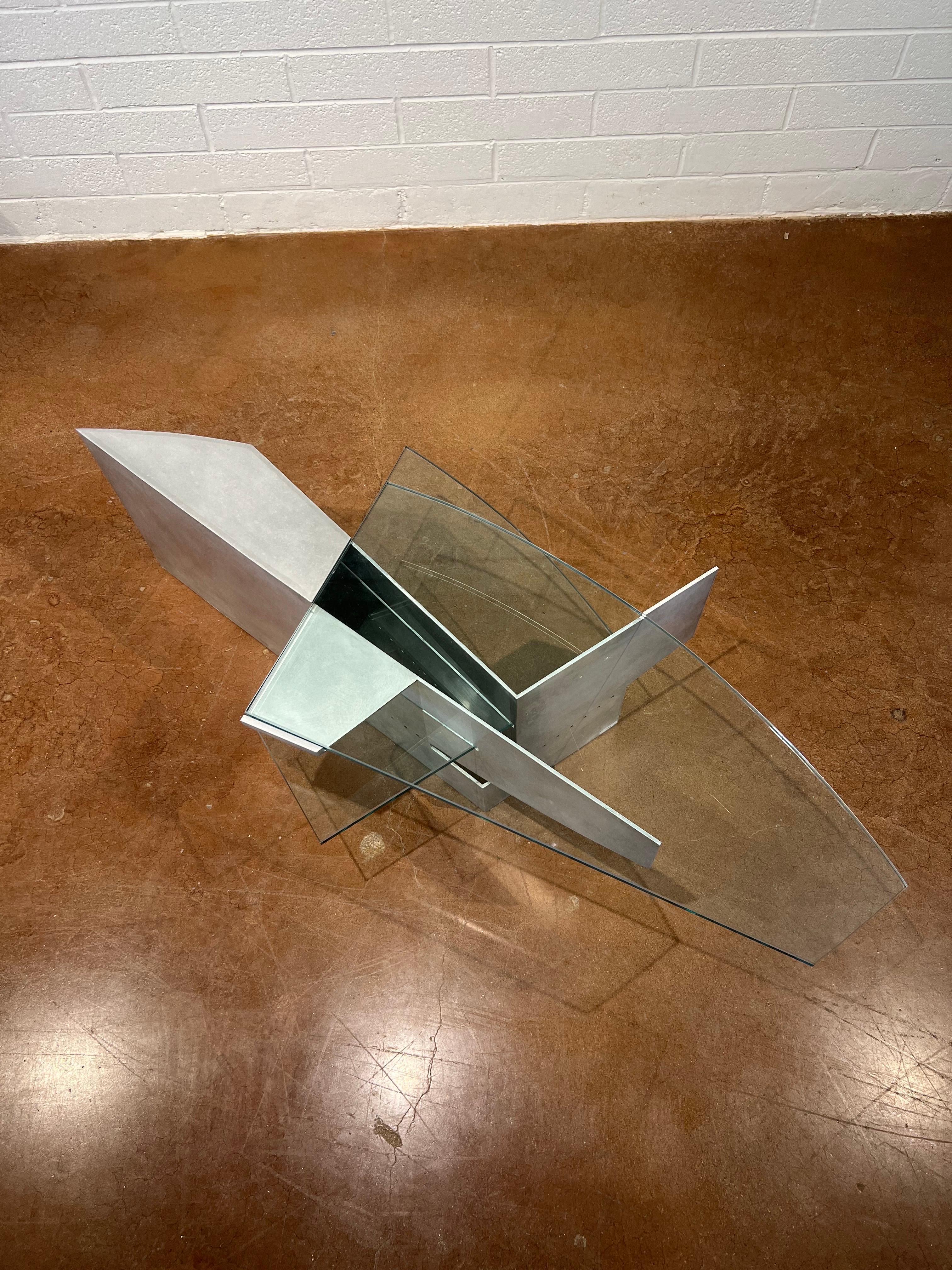 This Robert Whitton coffee table, crafted from aluminum and glass, is a striking example of design excellence from the late 20th century. Produced during the 1980s and early 1990s, the table exemplifies the era's innovative use of industrial