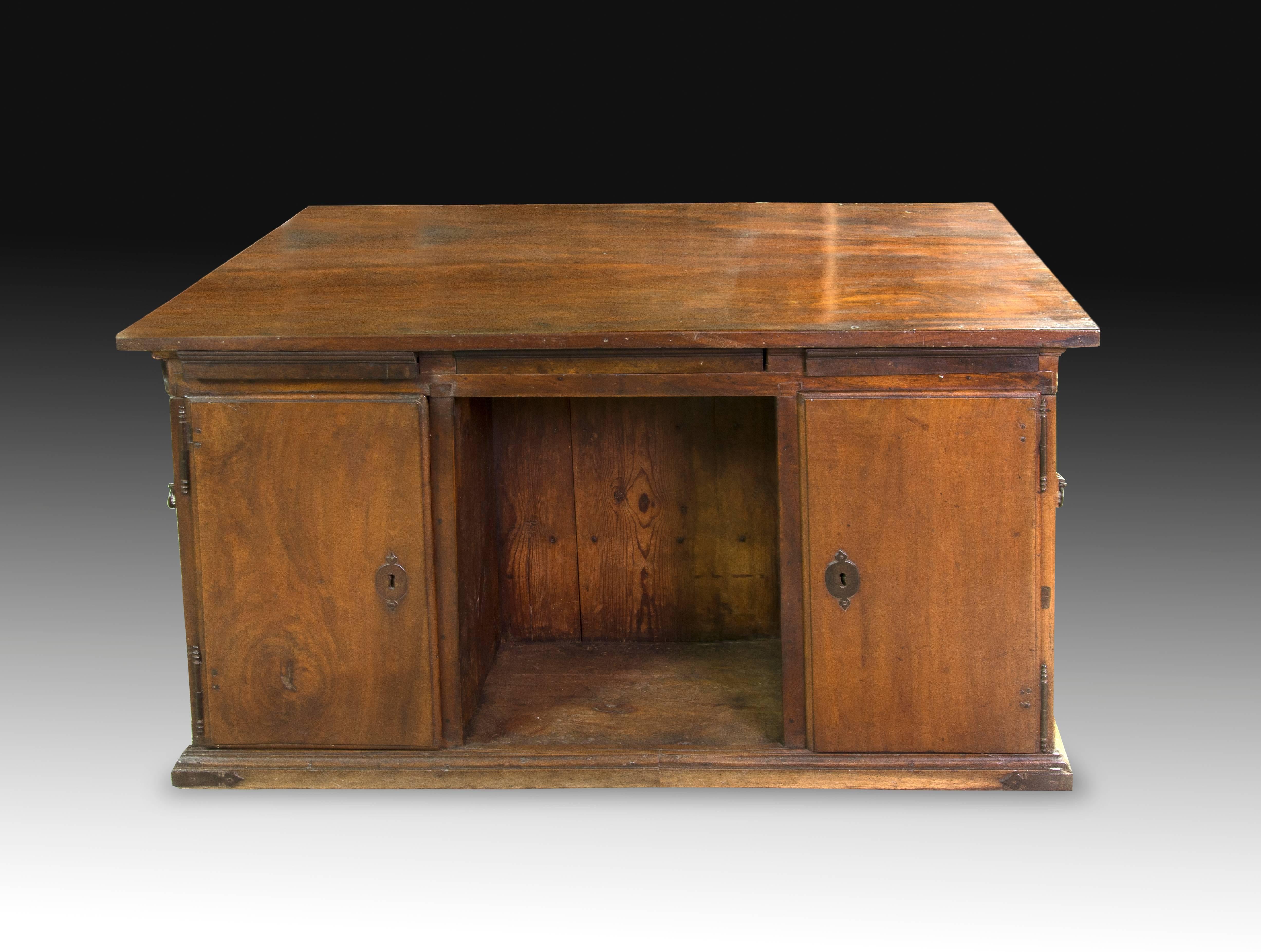 Architect’s desk. Walnut; mahogany tabletop; metal. 18th century.
 The decorative carving that this desk presents (simple moldings on the lower part, panels on the sides and moldings on the upper part, under the board) enhance the wood and the