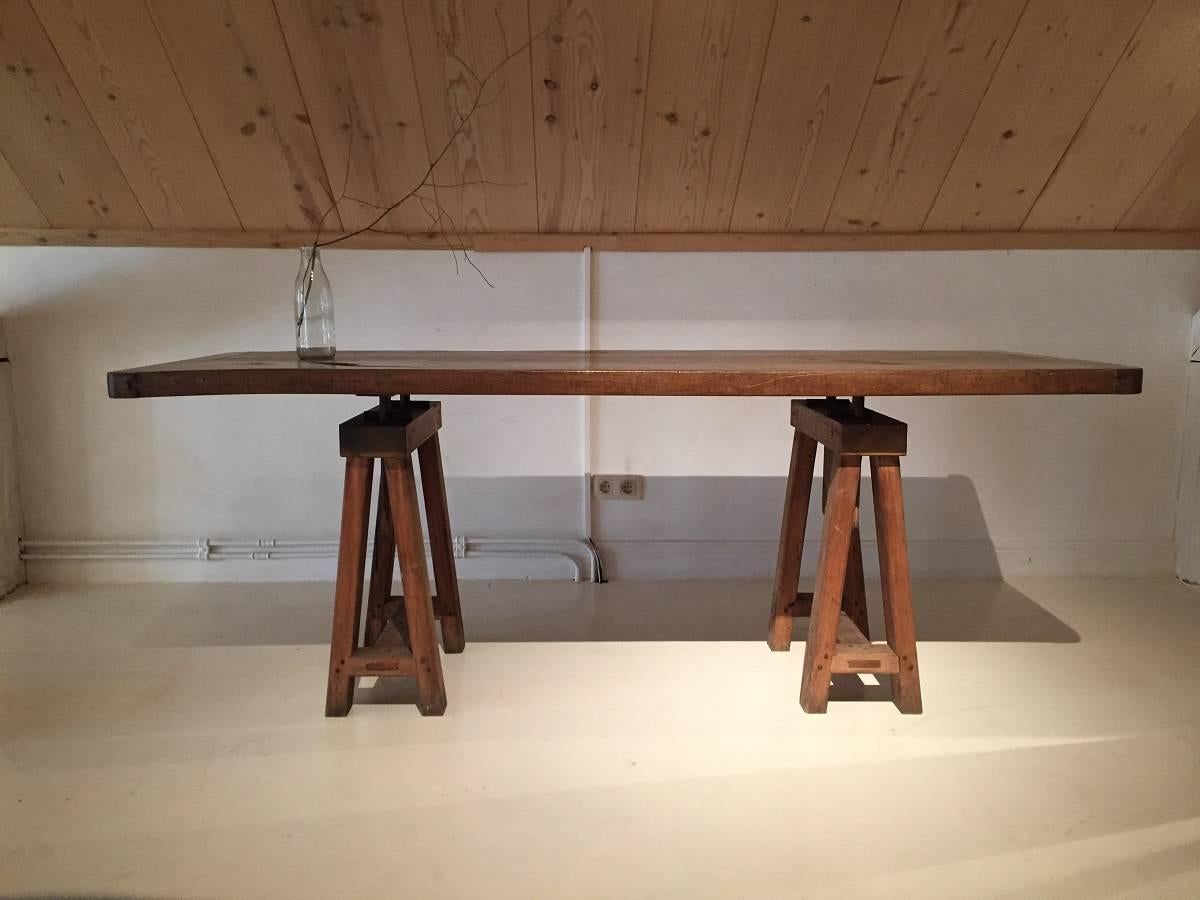This 19th century English drafts table has clean sober lines and is also quite fictional as a writing or kitchen table. Its made from softwood adjustable trestles which allows the top to go higher. The two board top is made from beautifully grained