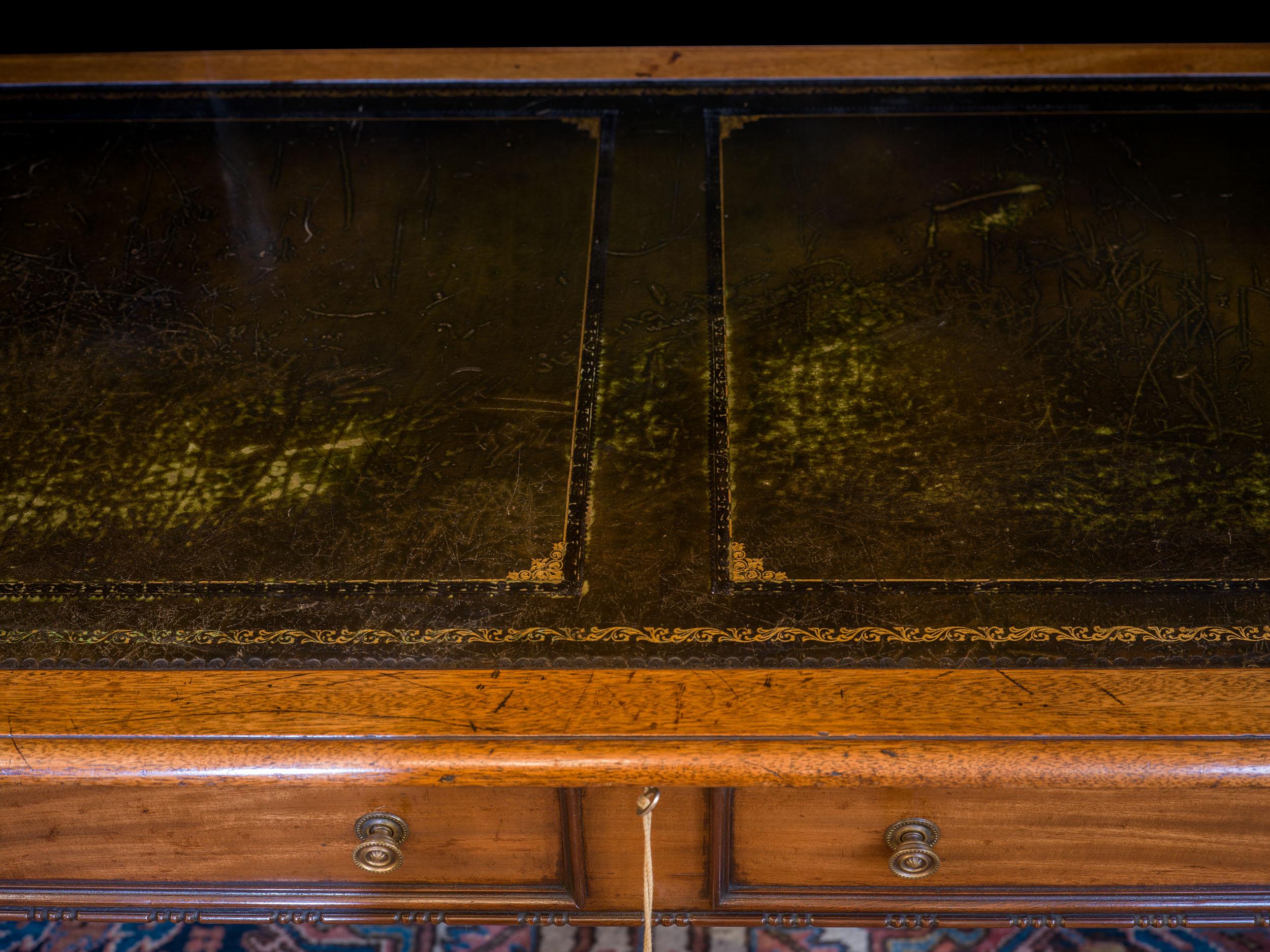 A rare William IV architect's plan table in mahogany, the top inset with gilt tooled leather above a hinged false drawer front revealing three baize lined trays, on carved bun feet and sunken castors.

English, c.1830.
