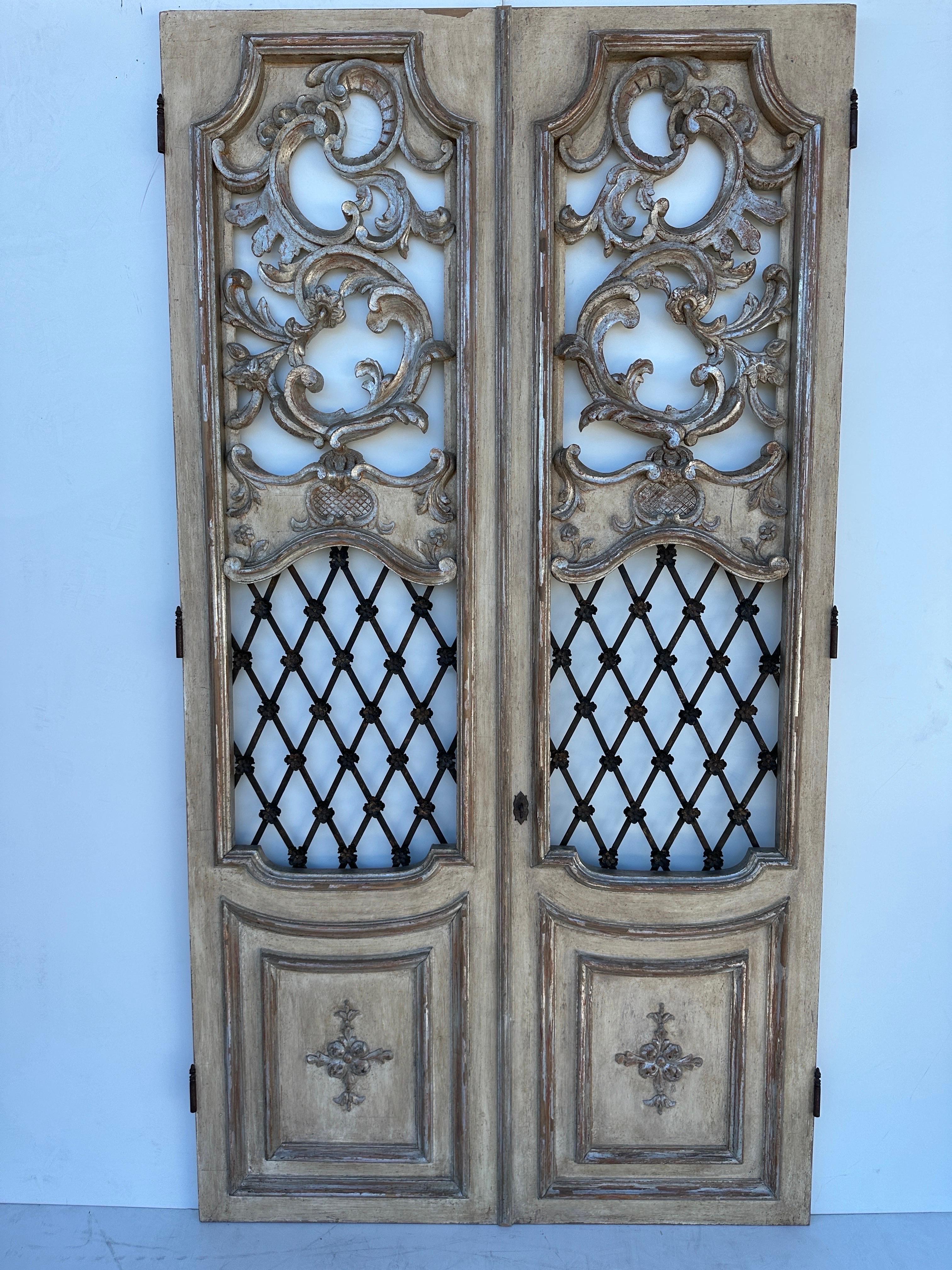Pair of architectural Italian style hand carved decorative doors with wrought iron grill and silver leaf detailing. These doors came off from Dennis and Leen 