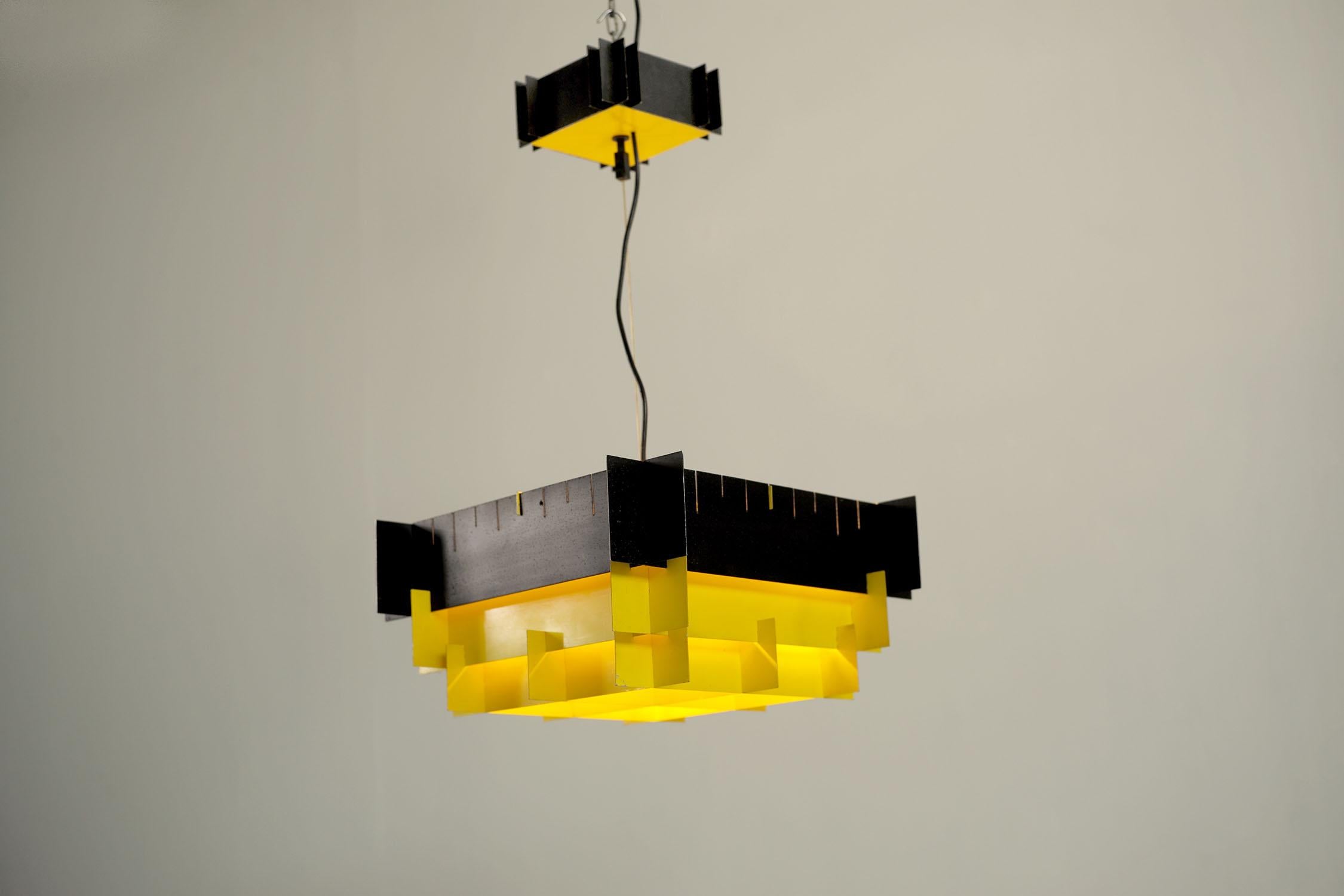 Architectural suspension with 4 lights in yellow and black lacquered metal, 1960. The metal blades come together to form a pyramid, the matte black lacquered upper band is perforated with vertical lines. The light, provided by 4 E27 bulbs, is very