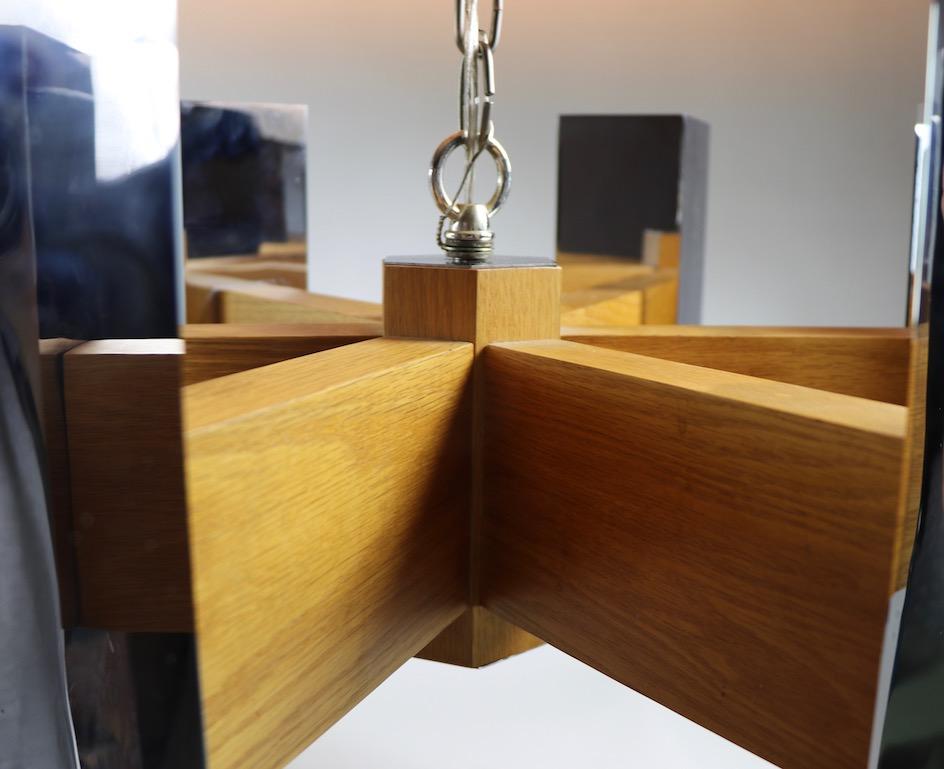 Masculine and substantial Modernist chandelier, having six arms which radiate out from the center post. Each solid oak arm supports a rectangular chrome box shade ( 12 x 3 x 3 ) which houses two sockets, up and down facing. The chandelier can be set