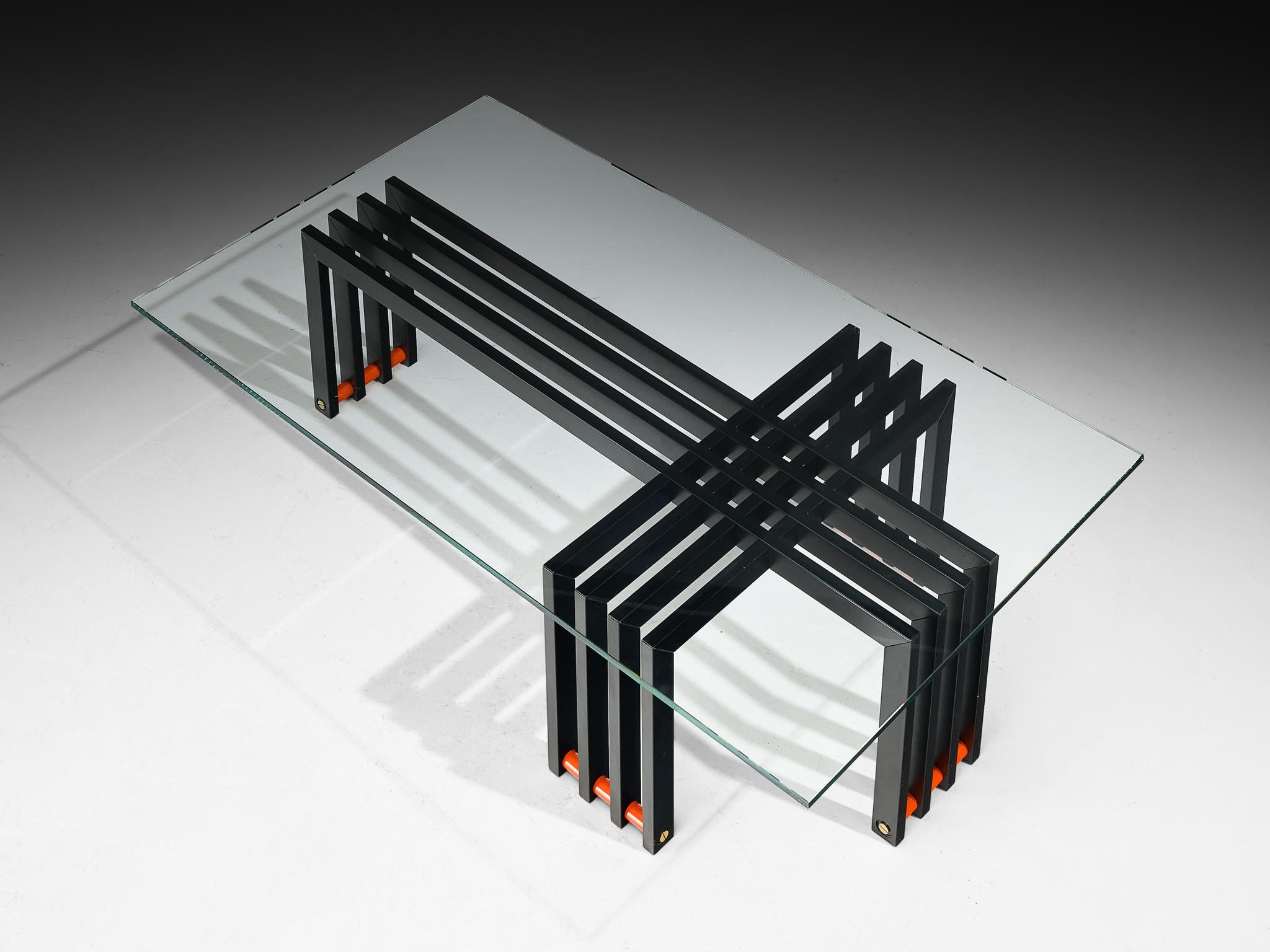 Table basse, verre, acier, Europe, années 1970.

Cette table basse sculpturale présente un plateau en verre transparent reposant sur un cadre géométrique saisissant accentué par des lattes rouges horizontales à la base. Quatre lattes de fer